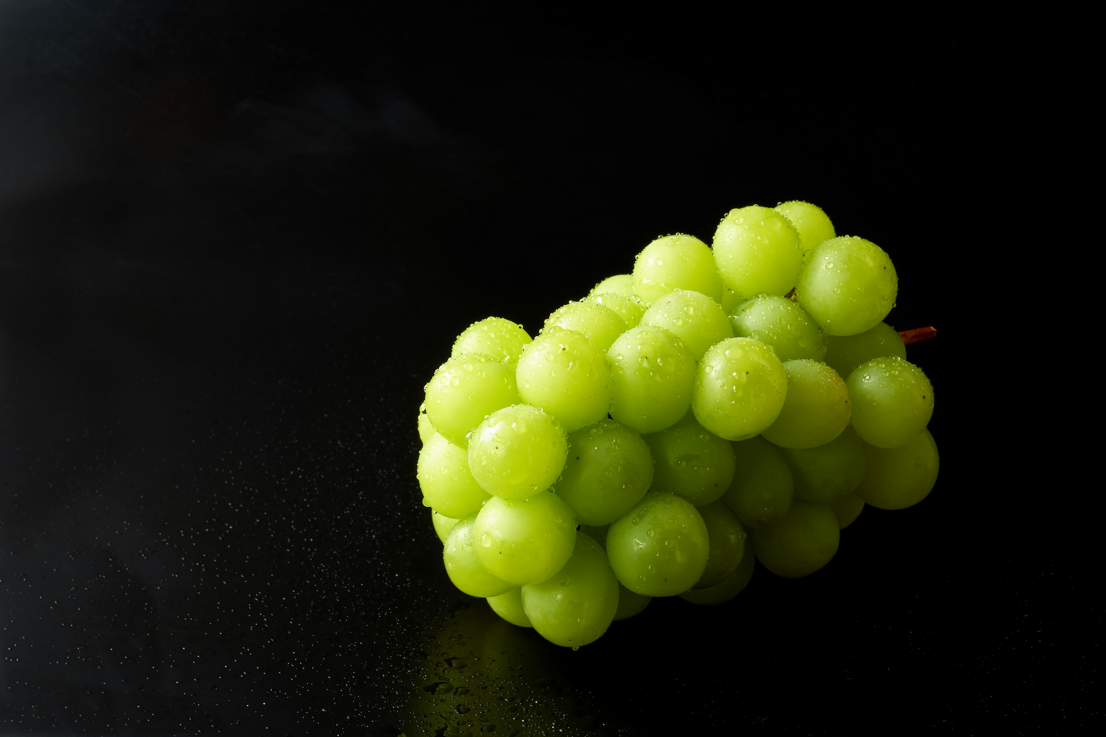 Racimo de uvas verdes frescas sobre un fondo negro