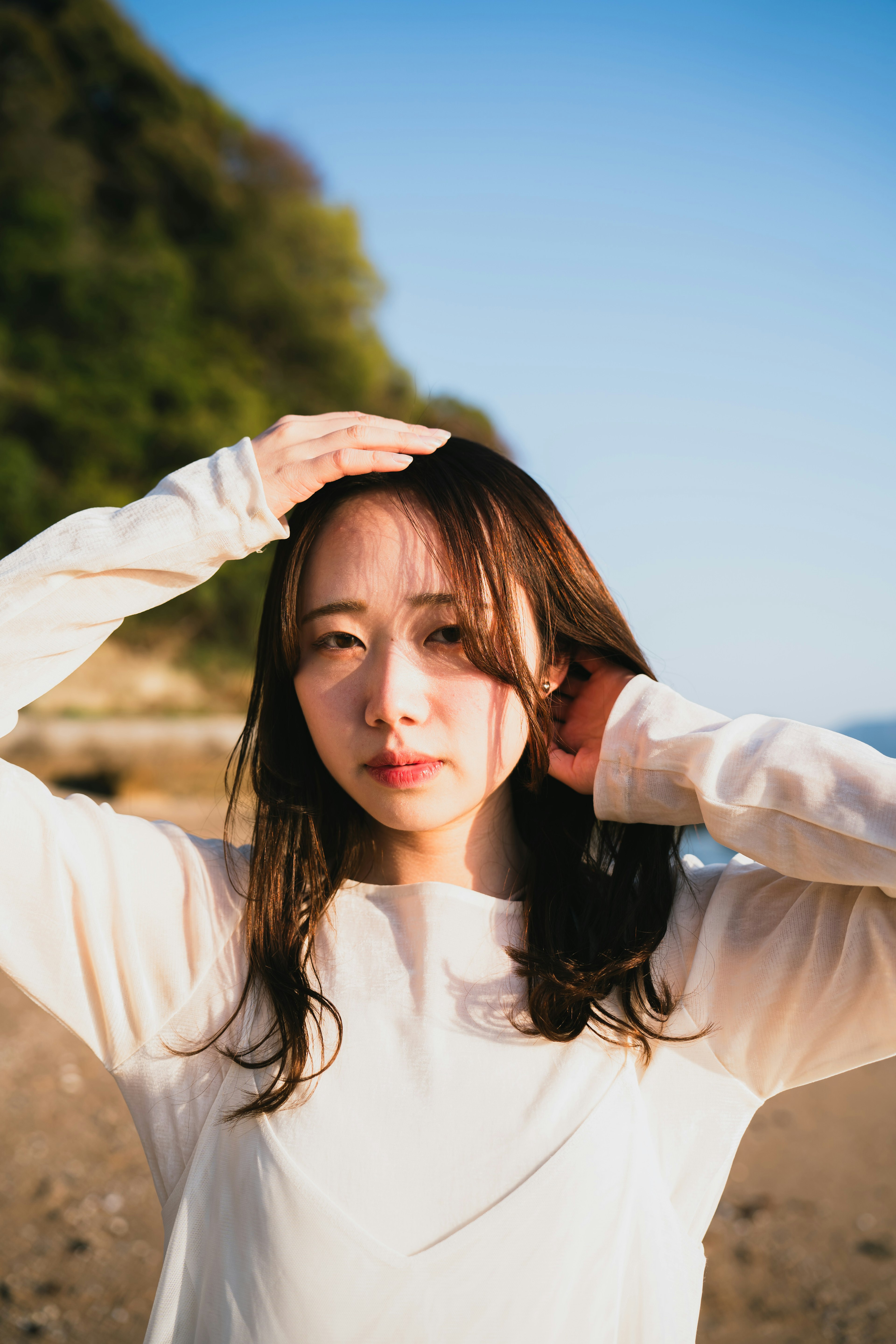 Porträt einer Frau, die sich am Strand die Haare richtet