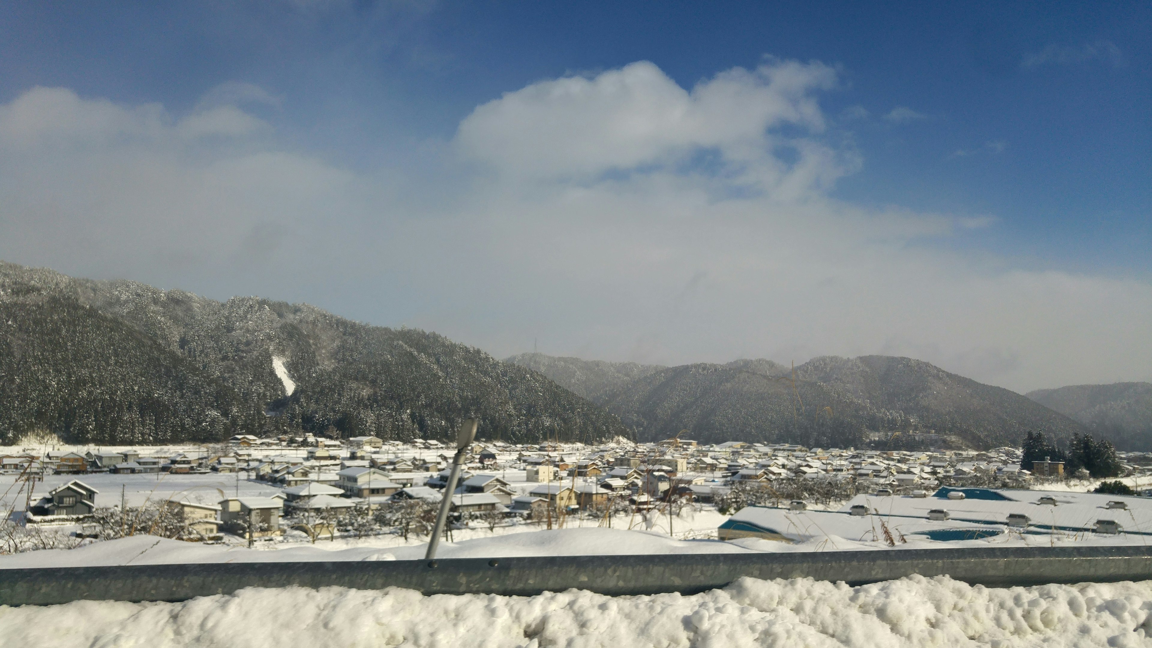 Snow-covered village with mountains in the background blue sky and clouds