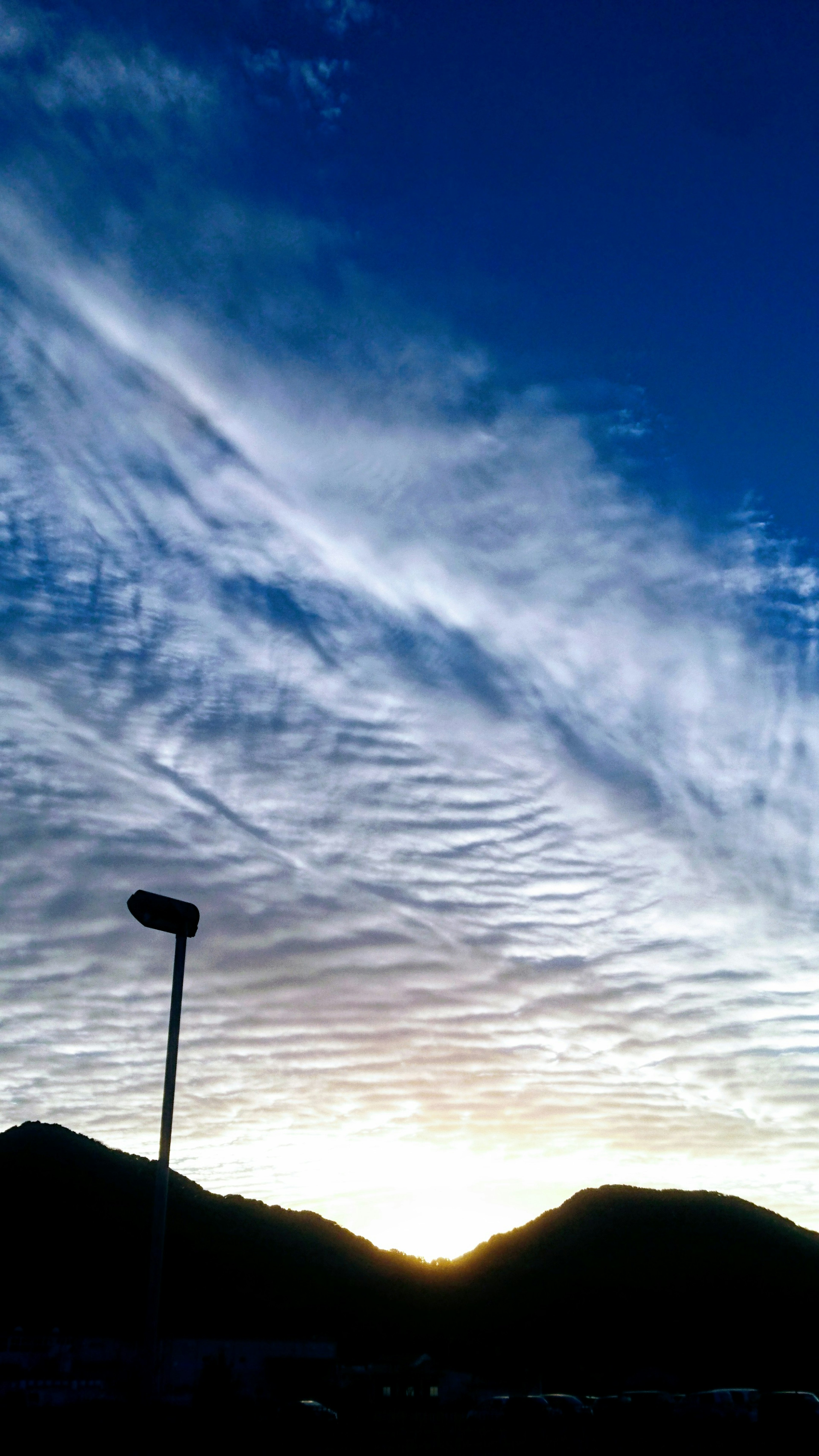 山の間から昇る夕日と青空に広がる雲