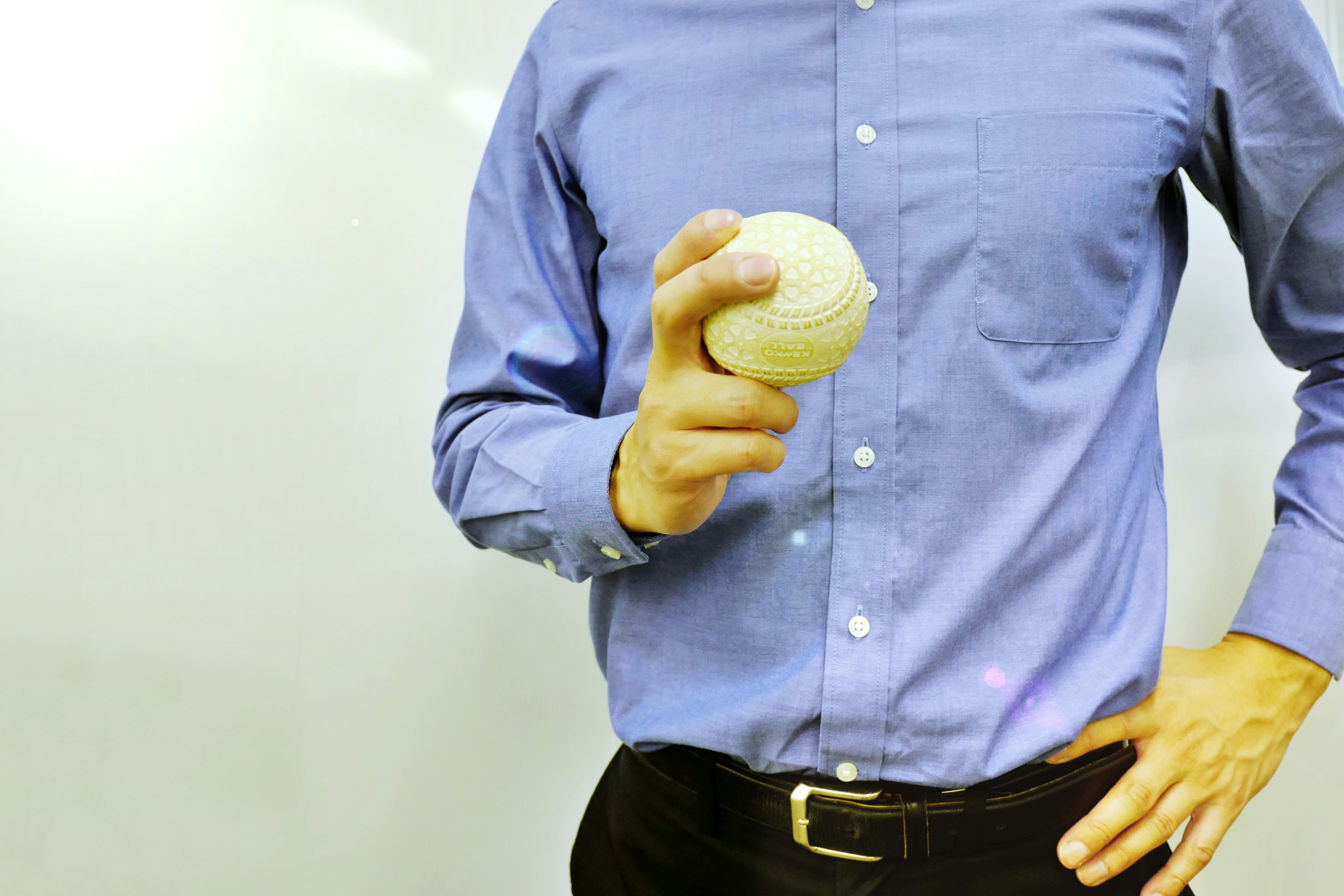 Un homme en chemise bleue tenant une balle blanche