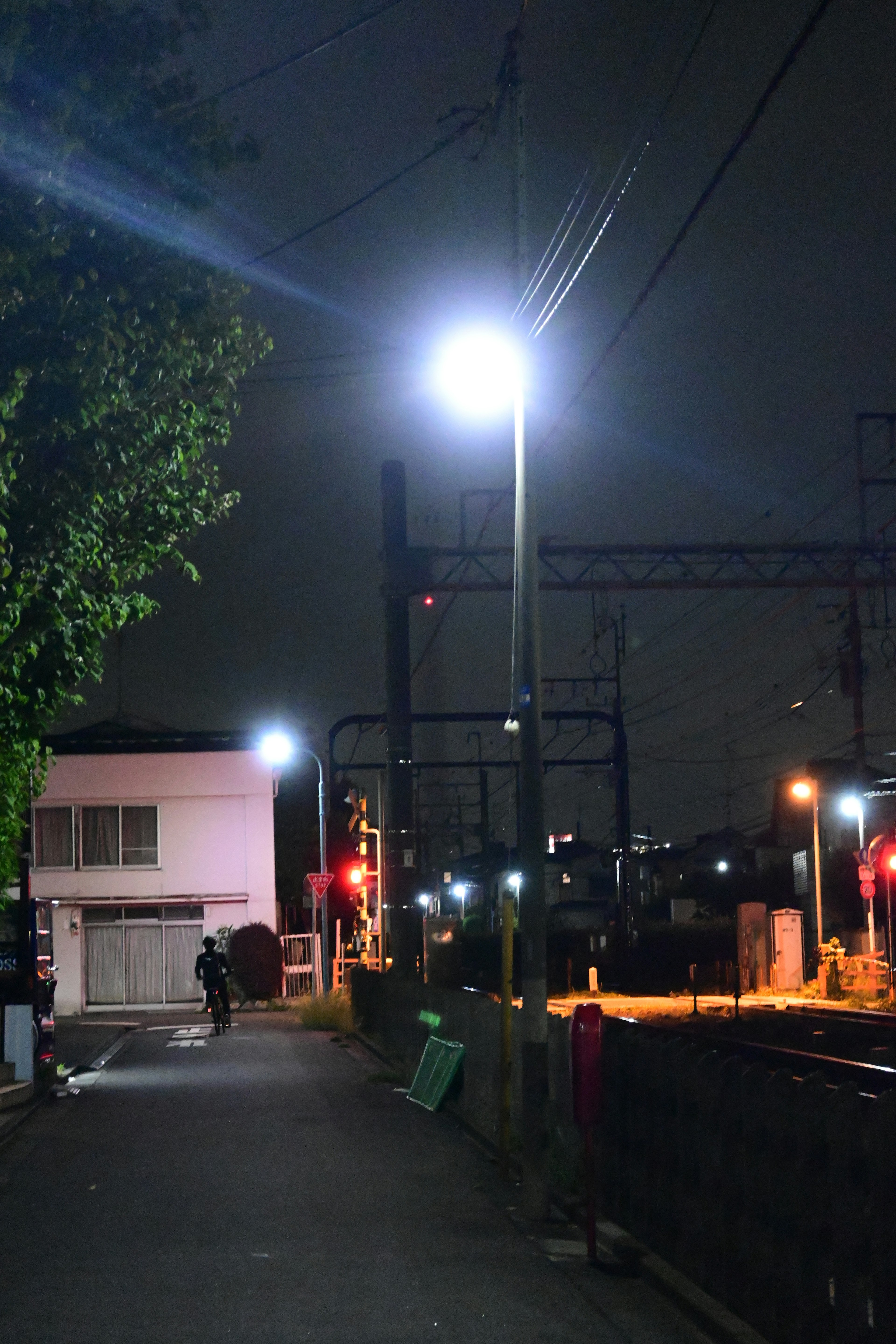 Jalan sepi di malam hari dengan lampu jalan dan rel kereta