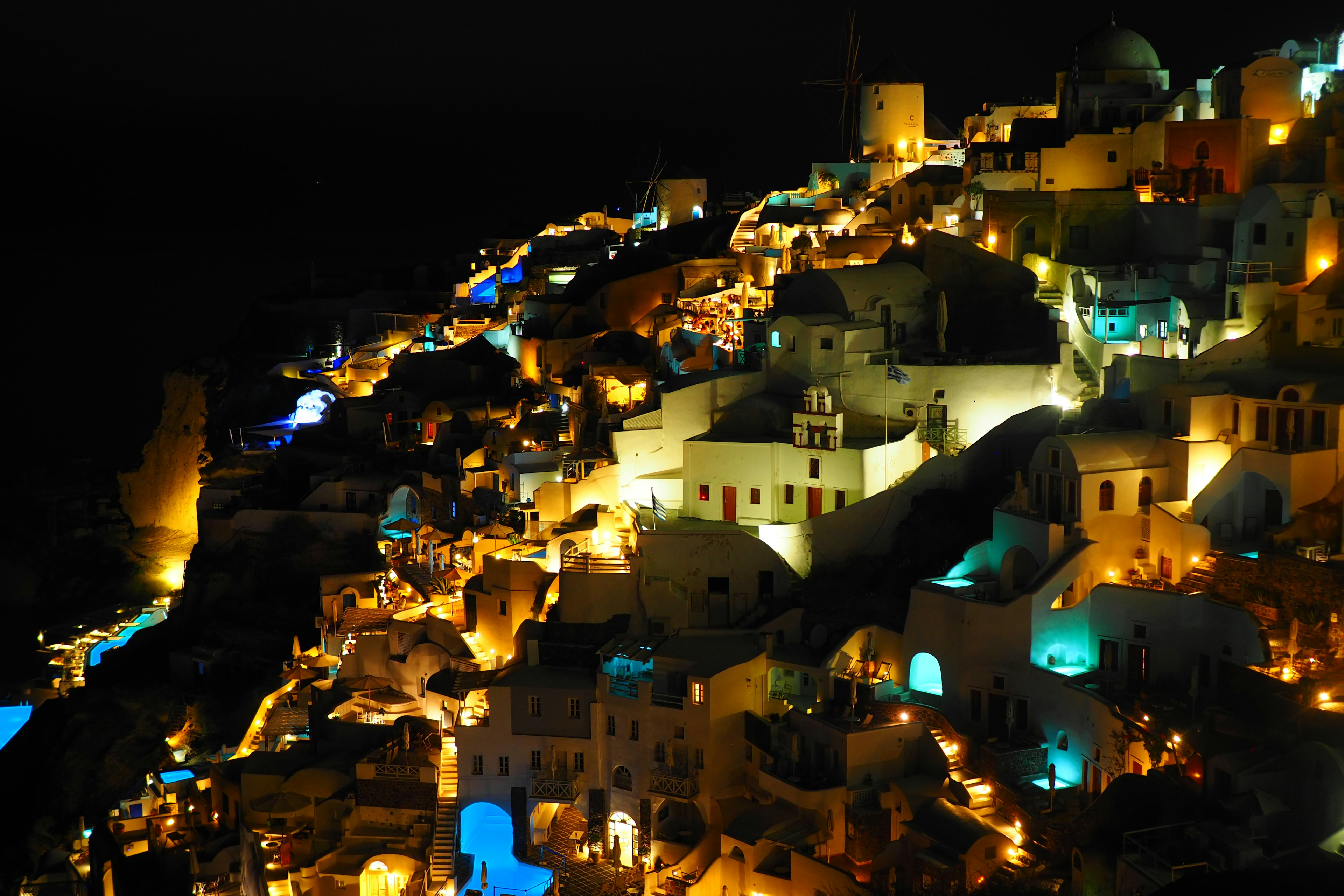 Vista nocturna de Santorini con edificios blancos iluminados