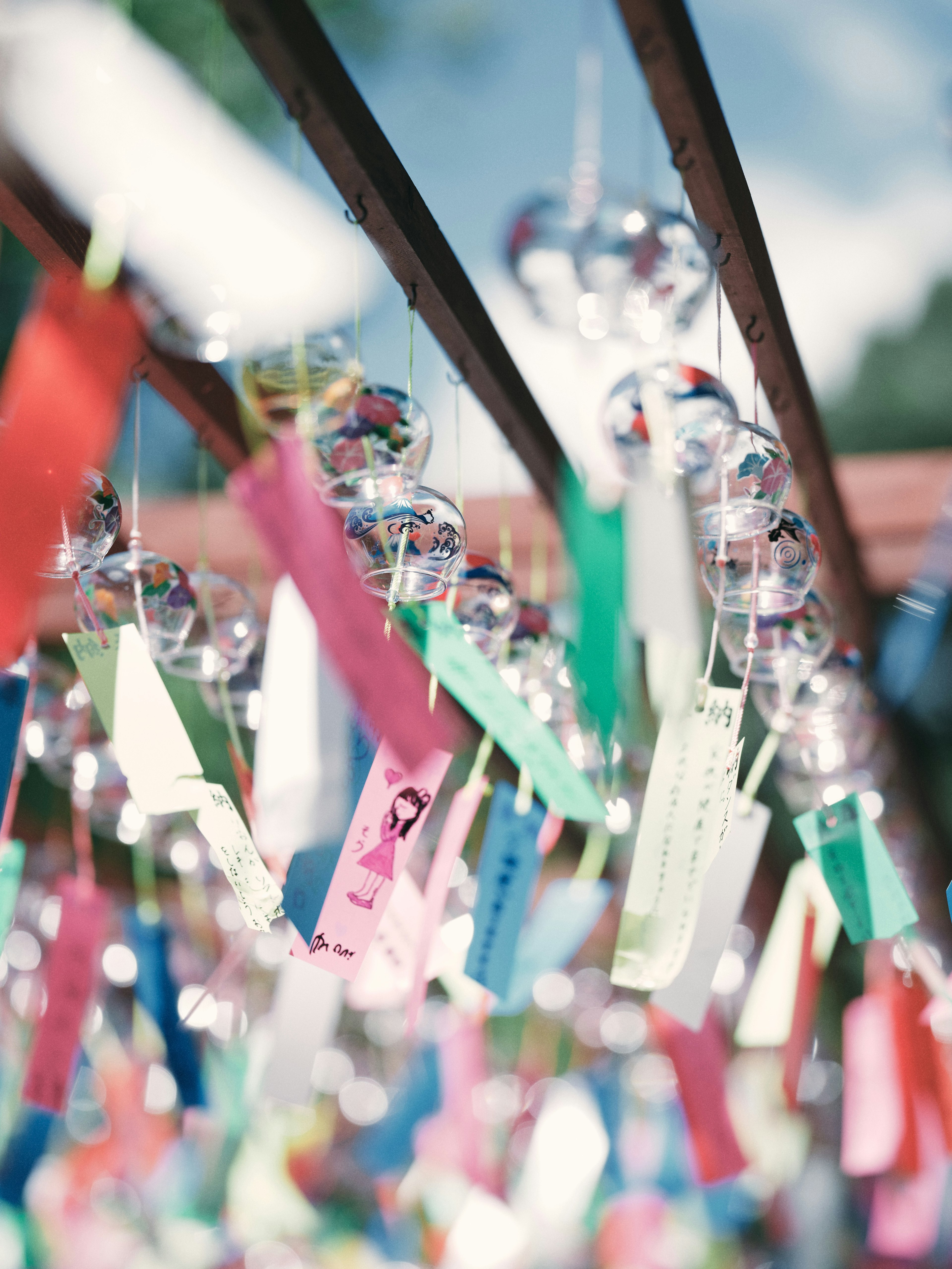 Colorful strips of paper and wind chimes hanging in a serene setting