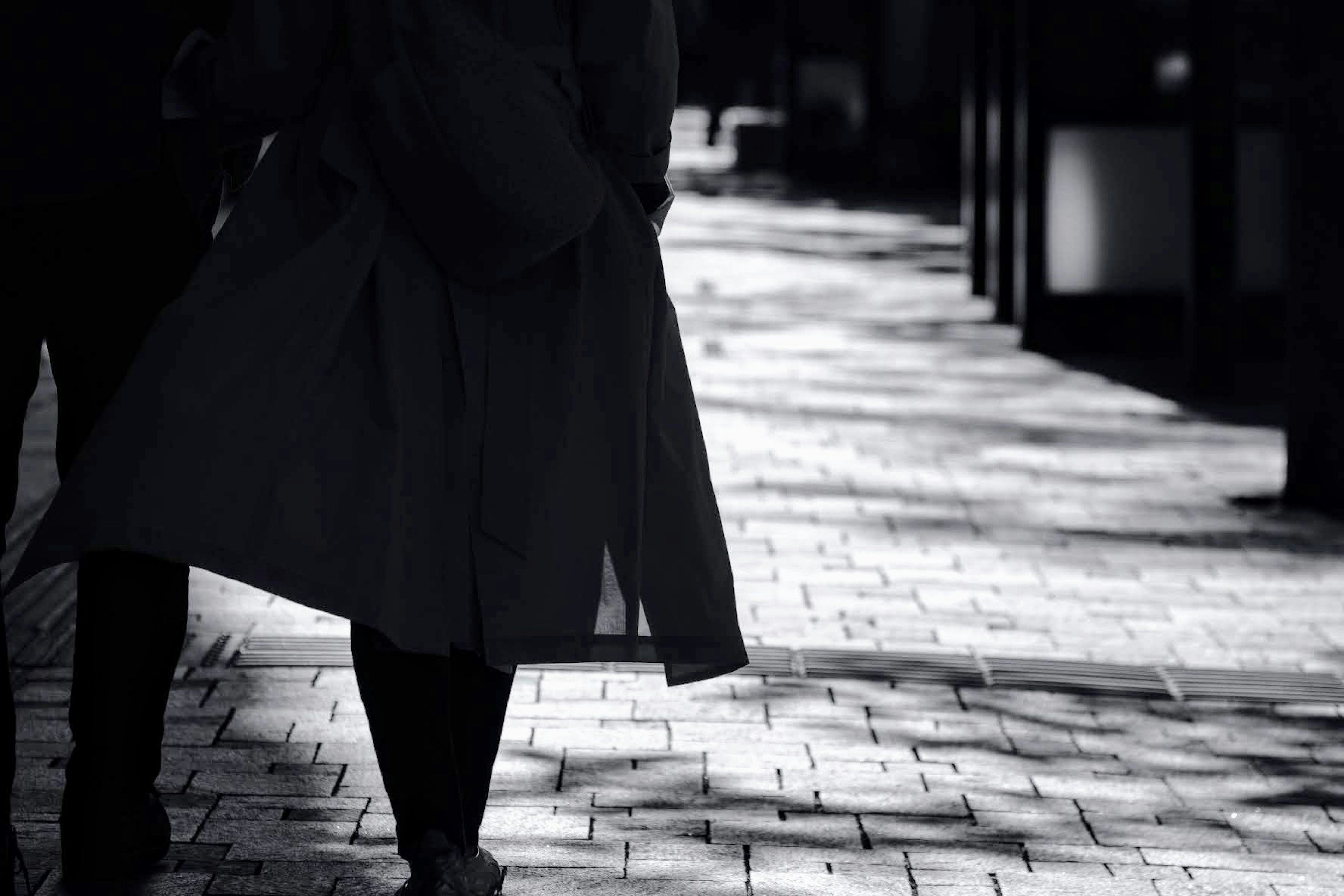 Silhouette of people walking on a shadowed street