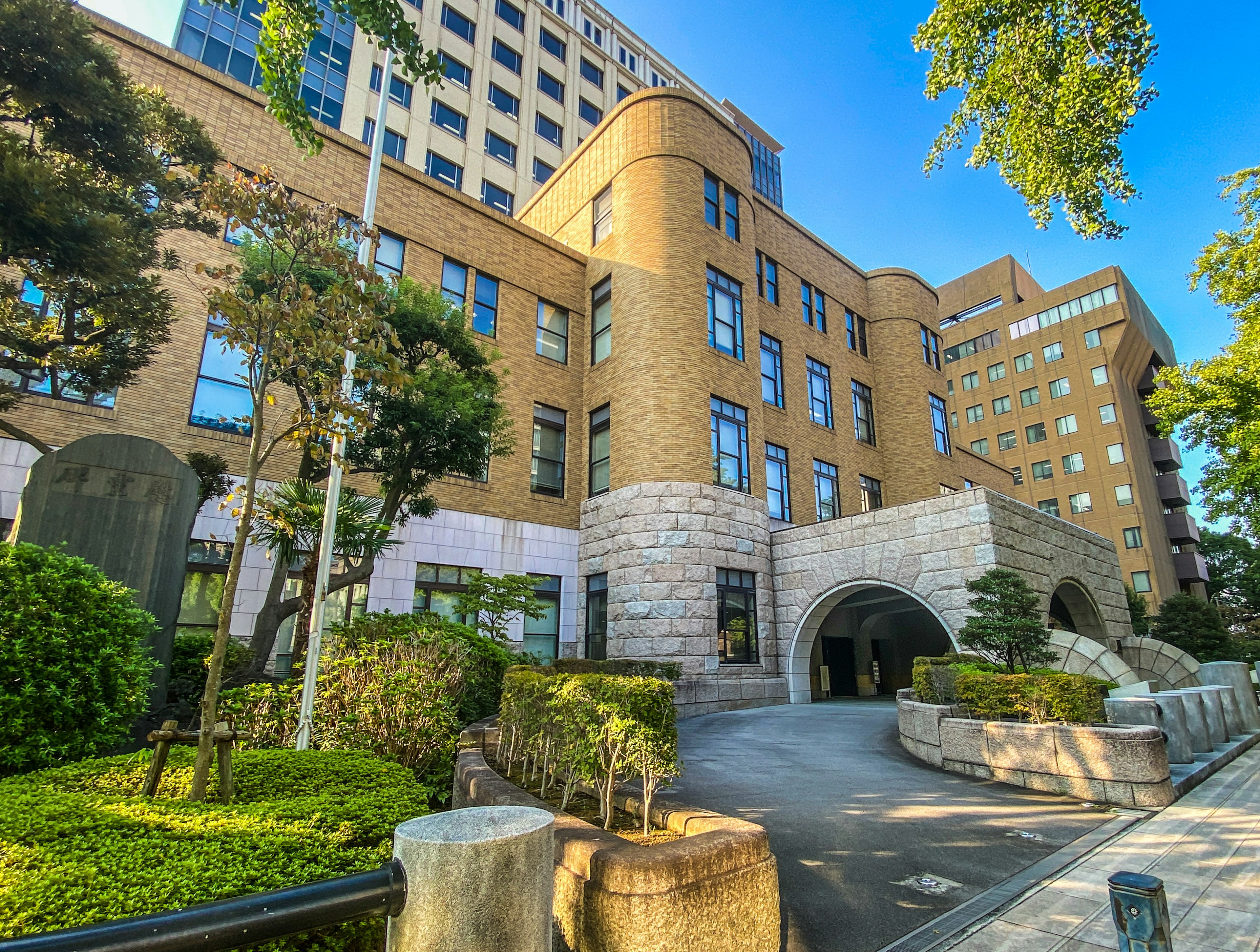 Modern building with reddish-brown facade and lush garden