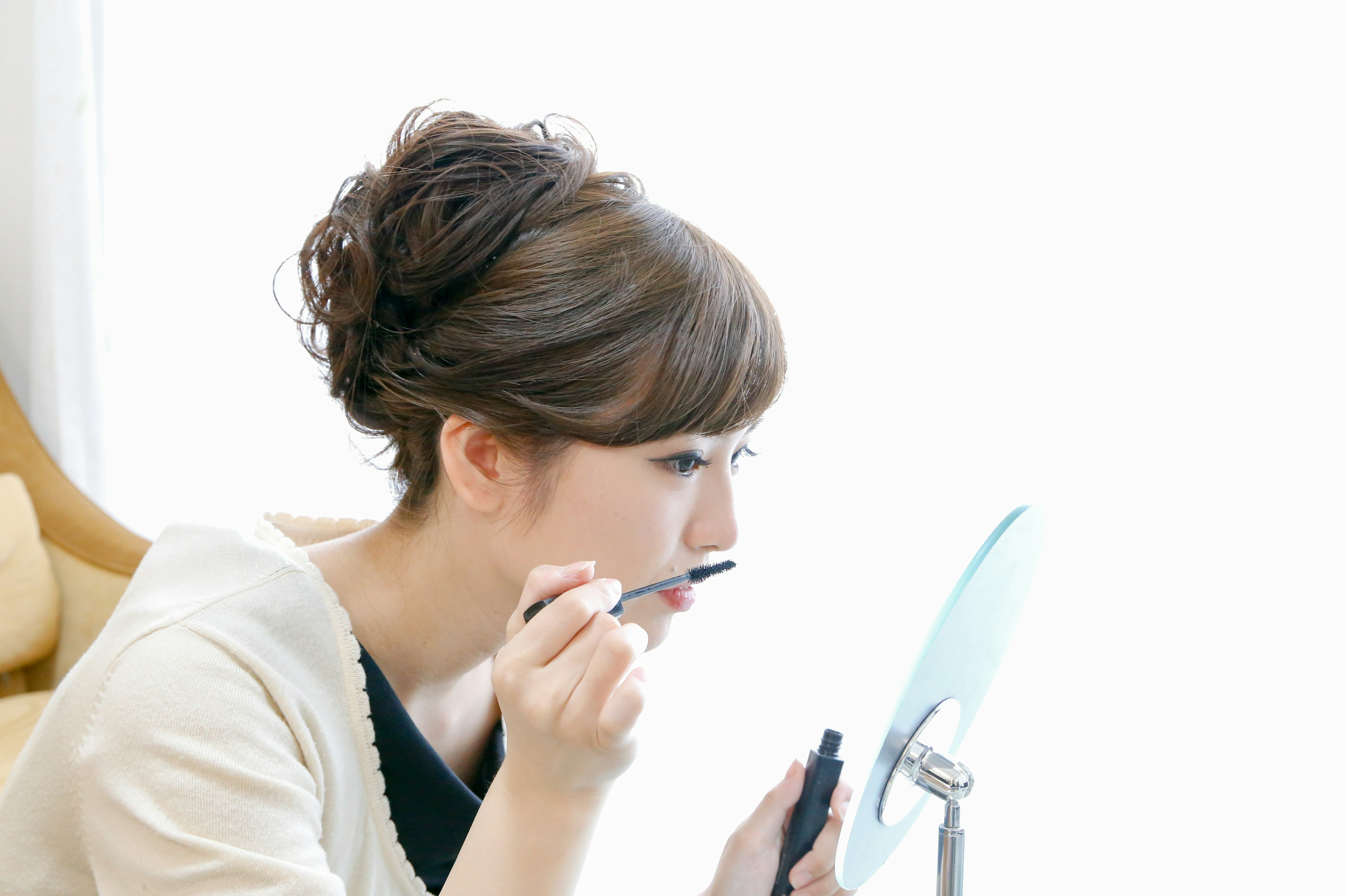 A woman applying makeup in front of a mirror