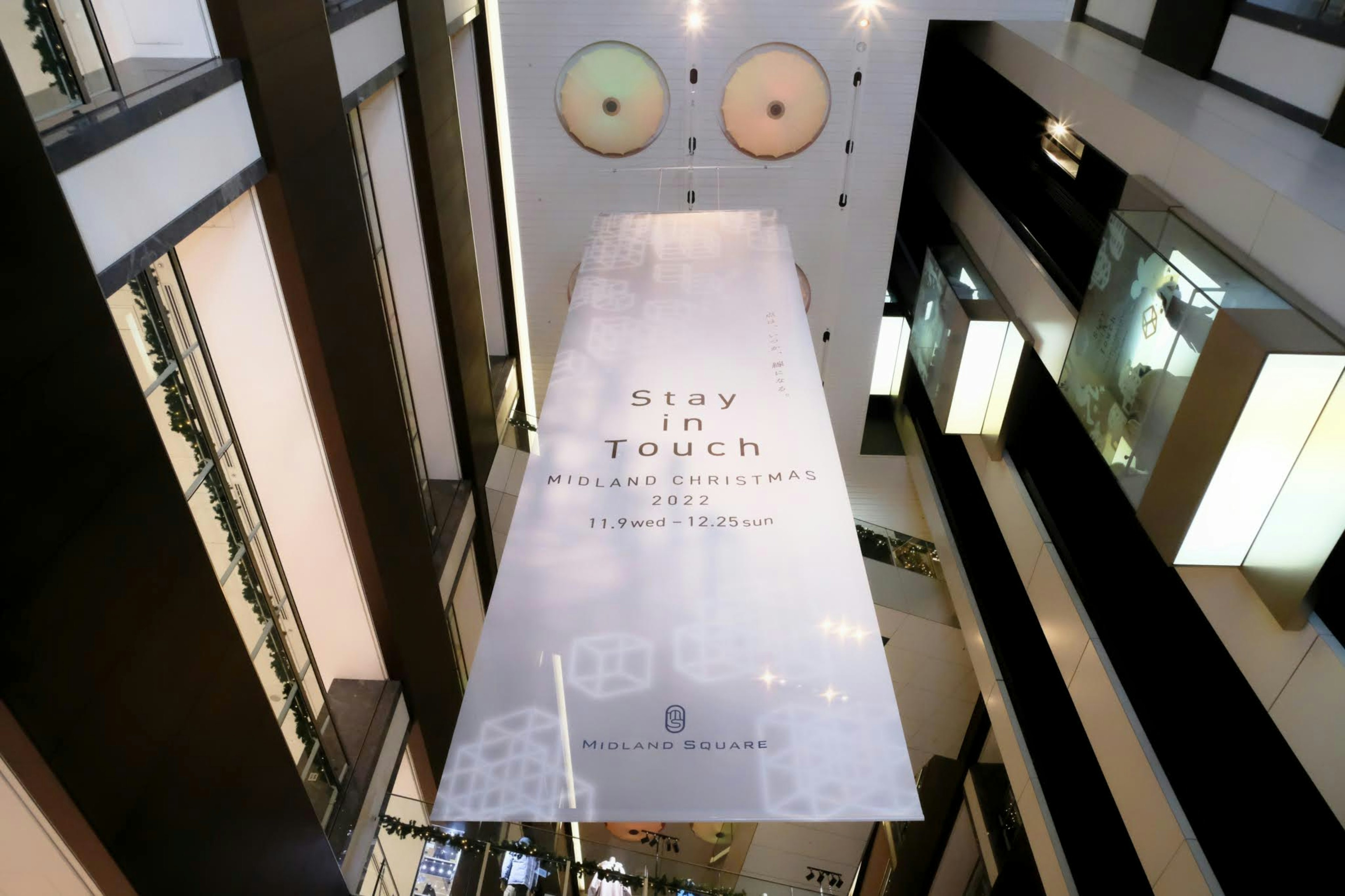 Large transparent banner hanging in an atrium with two round lights