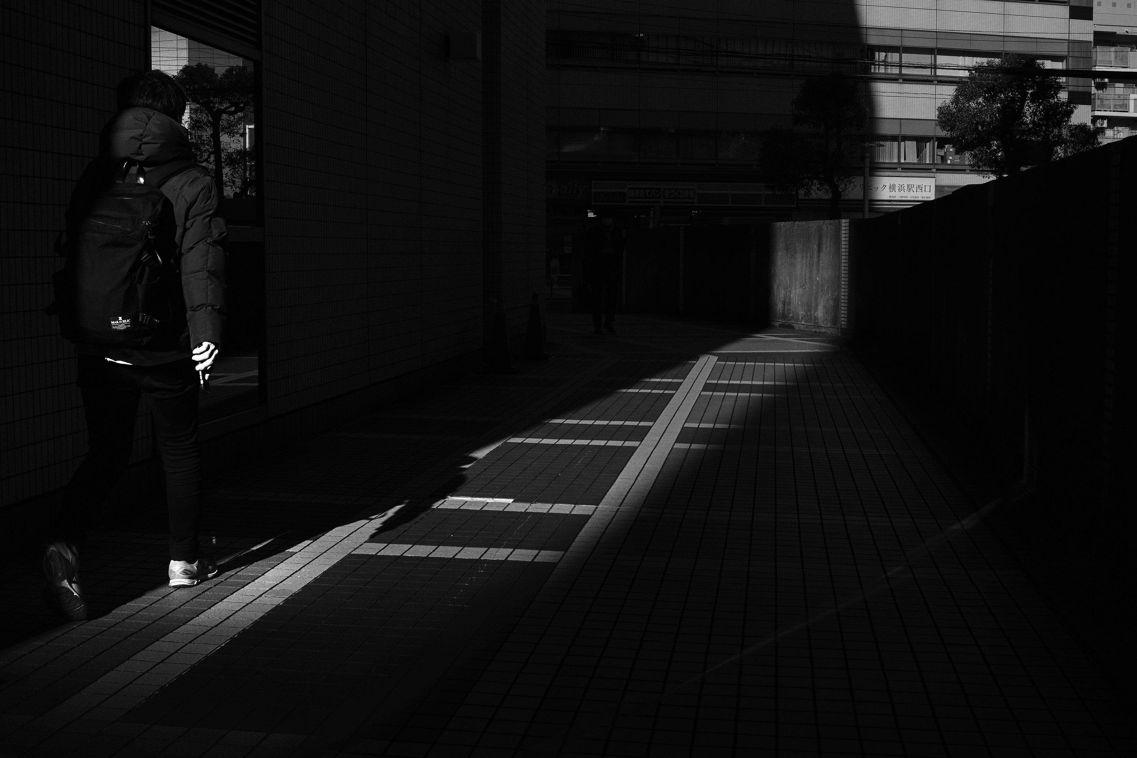 Monochrome photo featuring a person standing in a dark corridor with striking shadow contrast