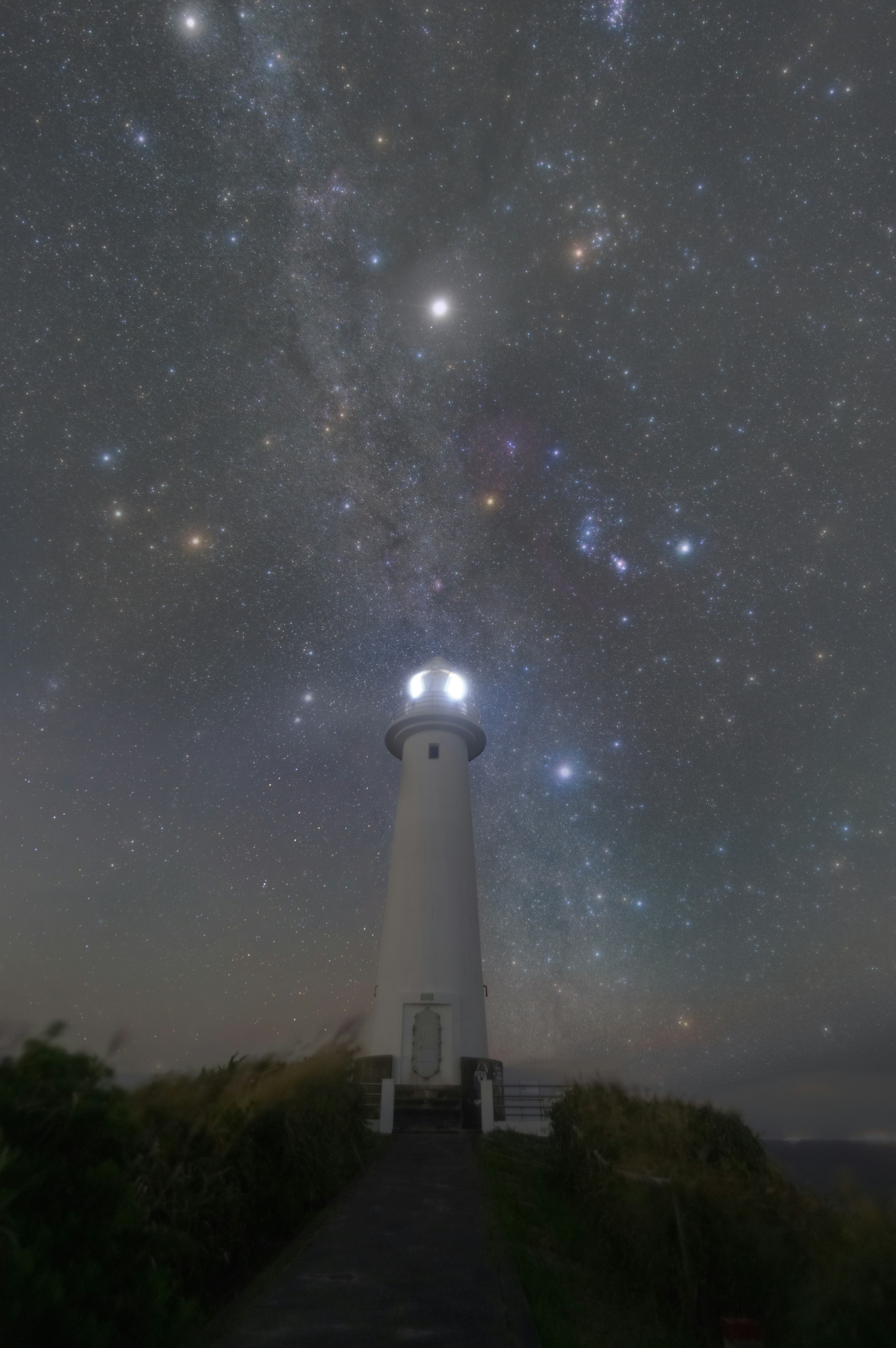 星空の下に立つ灯台の夜景