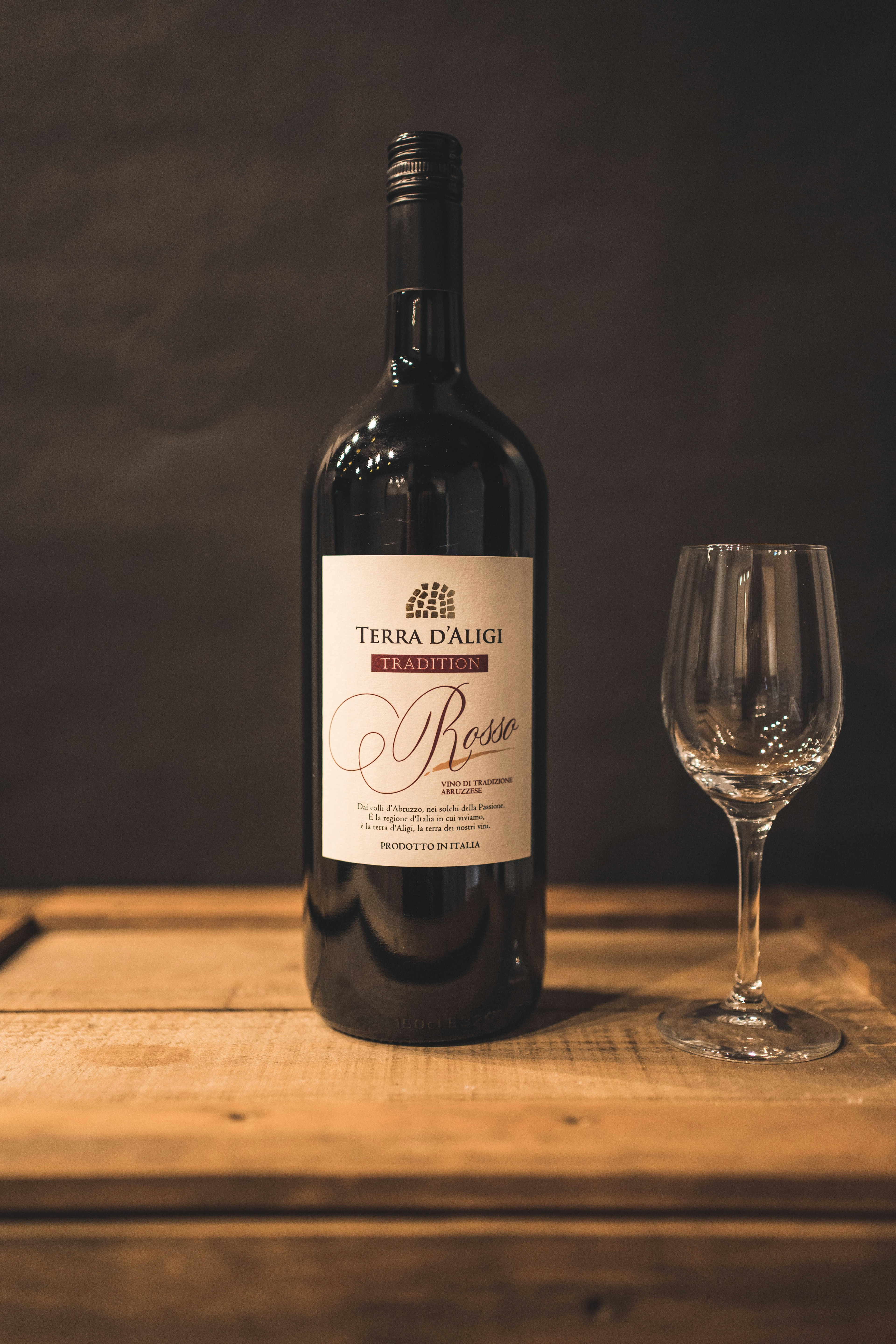 A red wine bottle and glass placed on a wooden table