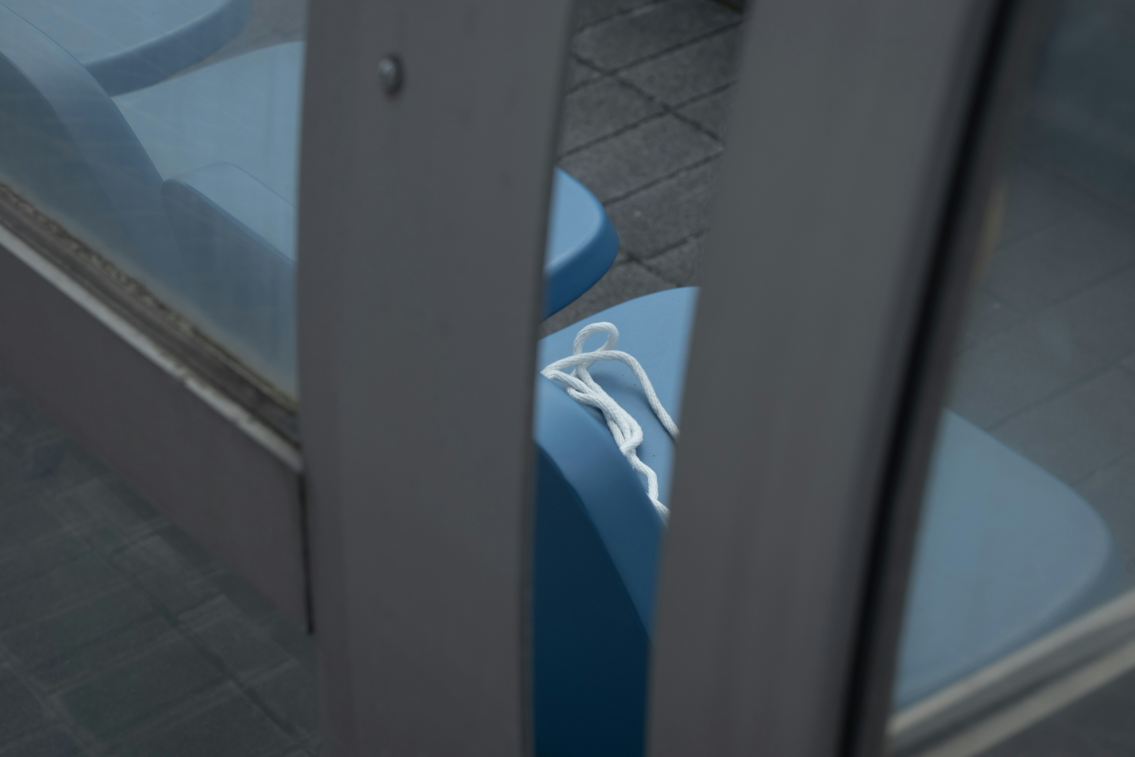 White earbuds lying between a blue bench and a glass door