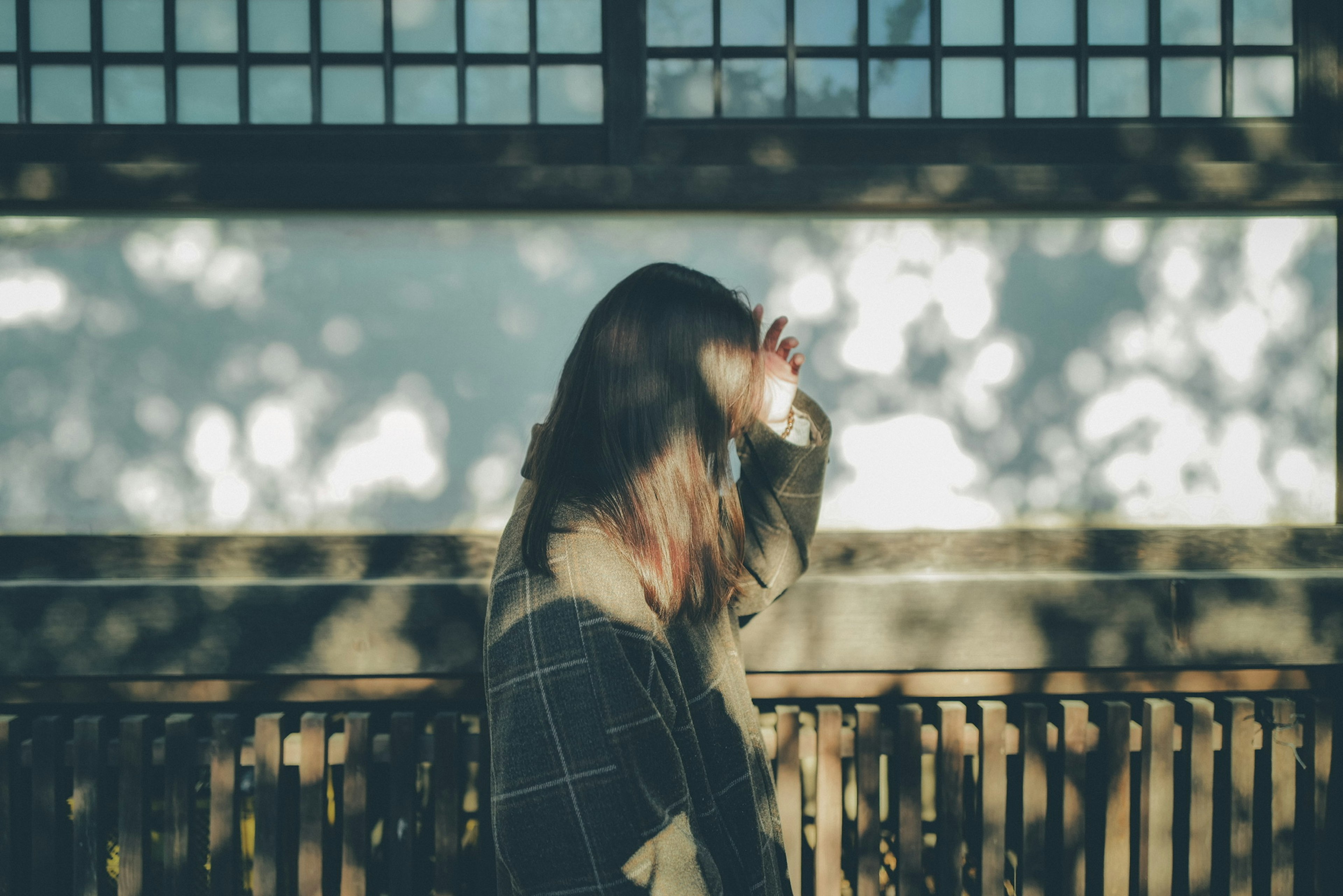 Silhouette einer Frau, die sich im gefleckten Sonnenlicht die Haare bürstet