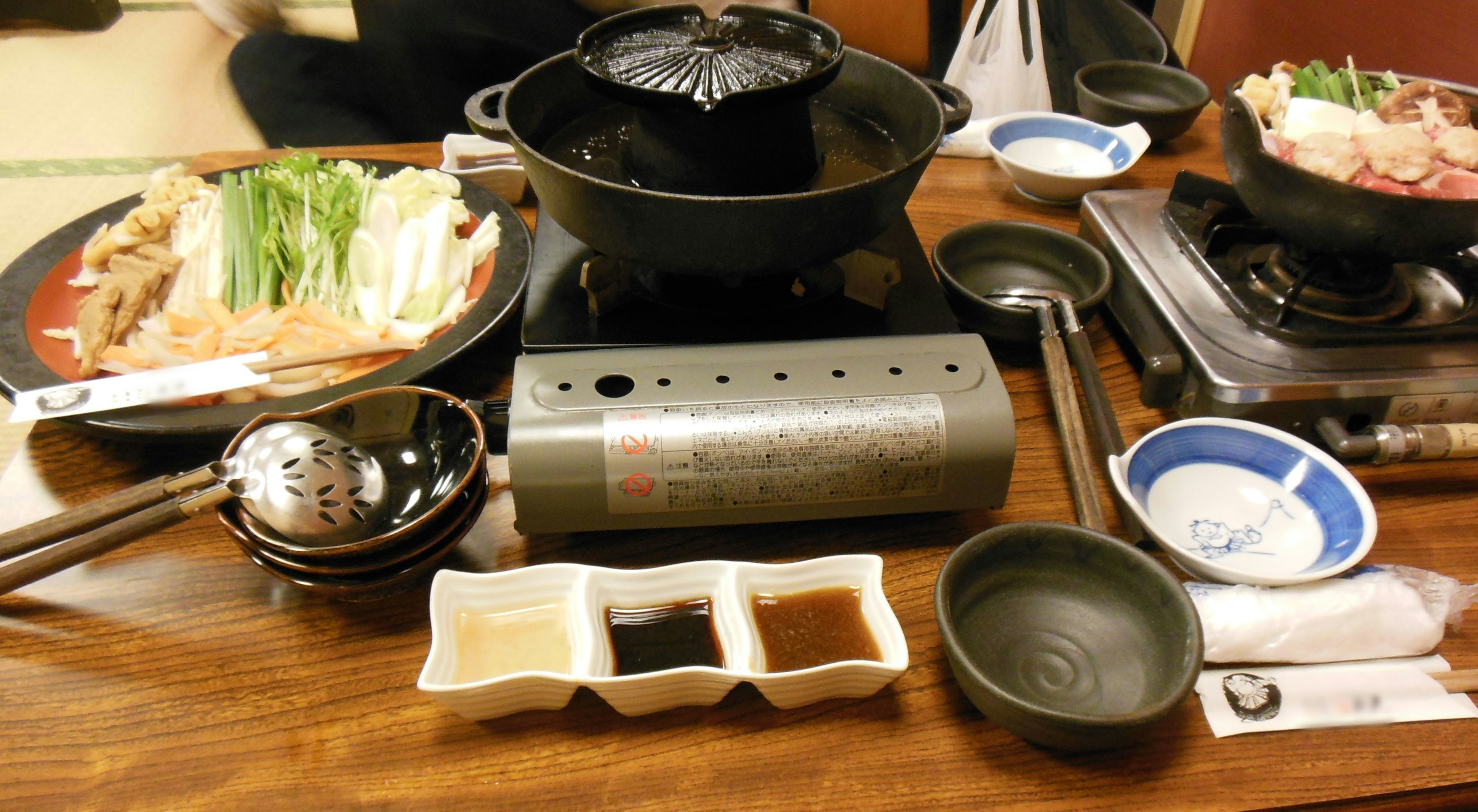 Tavolo con ingredienti per hot pot tra cui verdure e carne insieme a salse