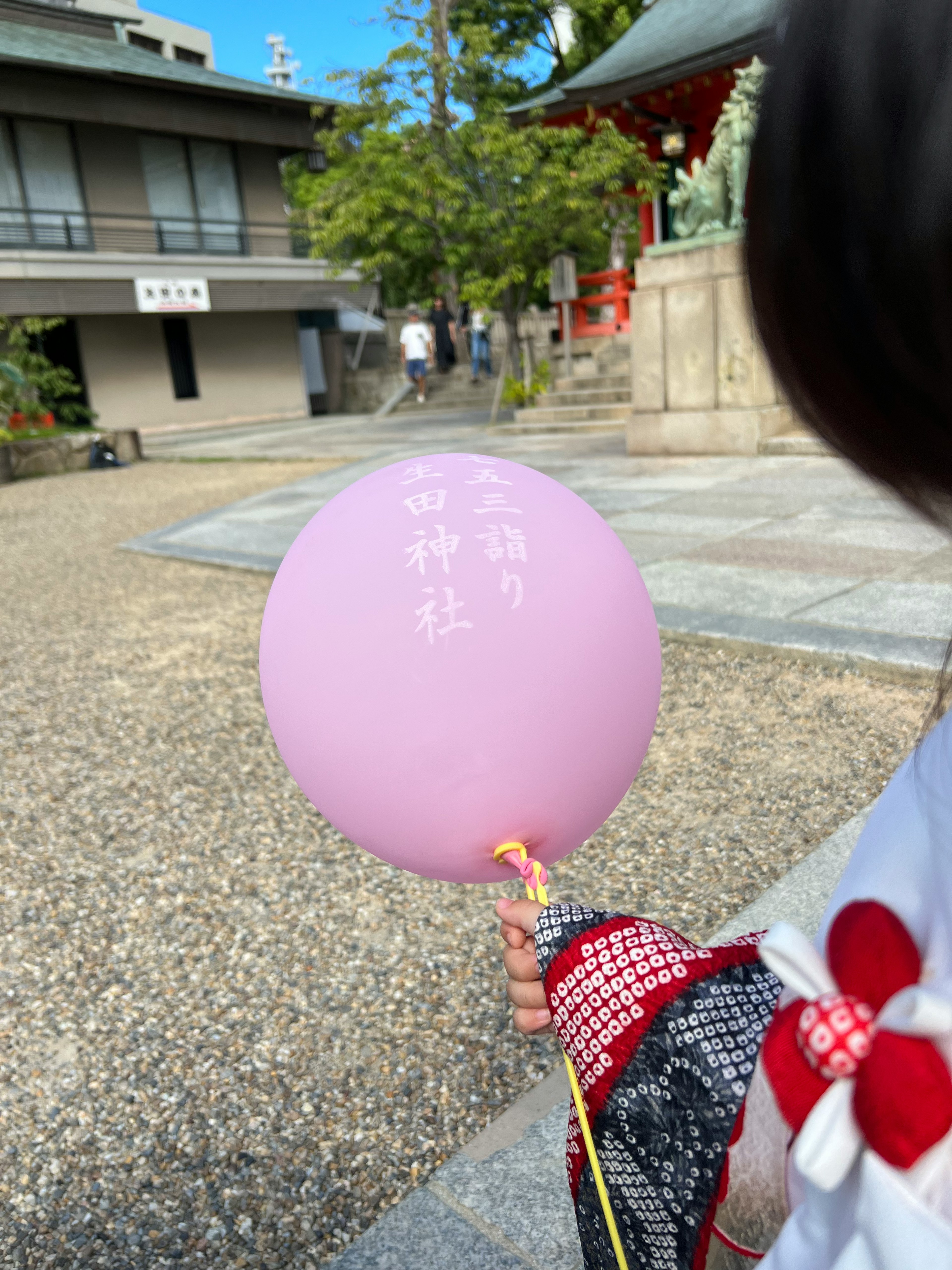 子供が持っている紫色の風船と伝統的な衣装背景に神社の建物