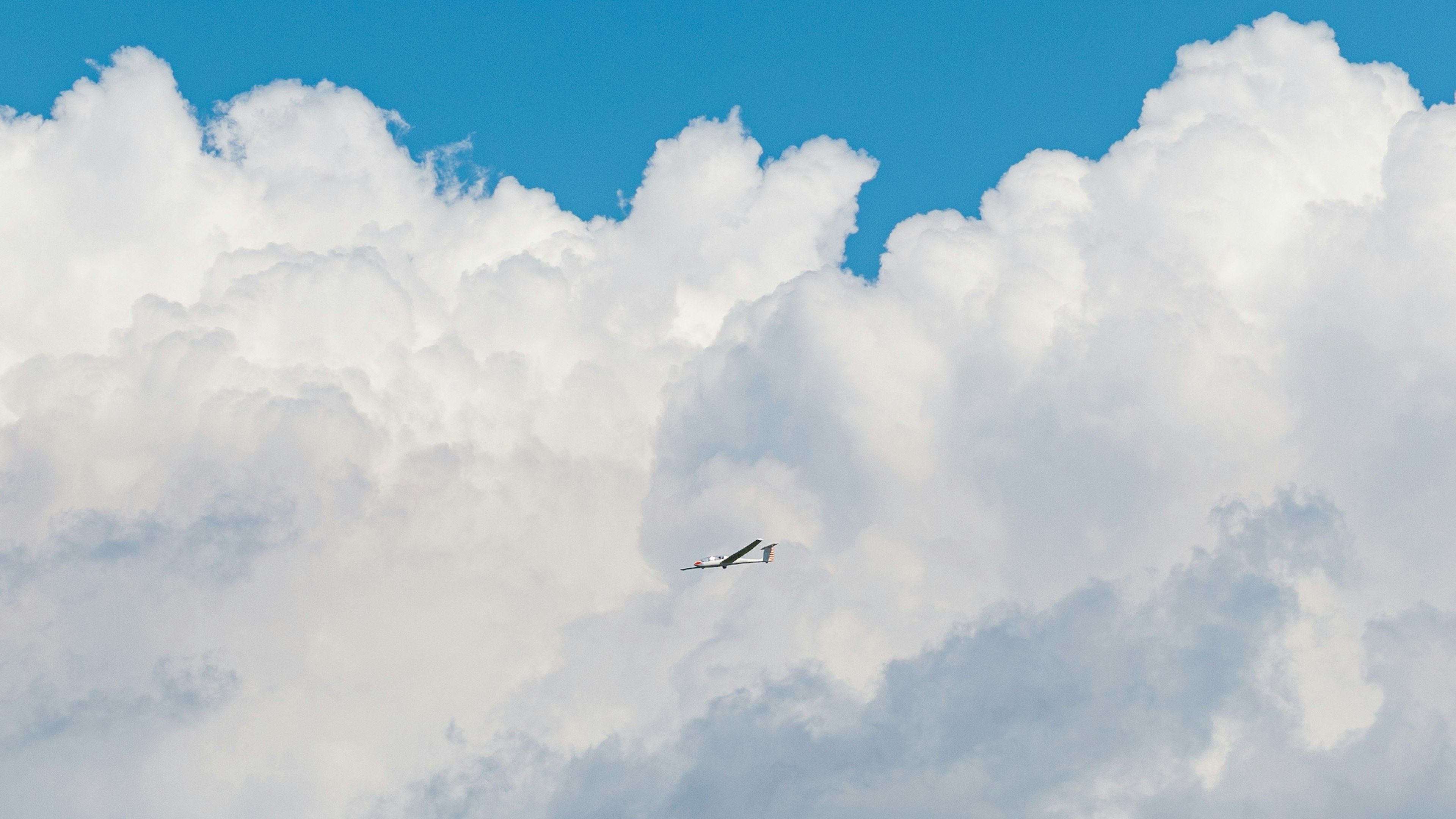 Kleines Flugzeug fliegt durch flauschige weiße Wolken vor einem blauen Himmel