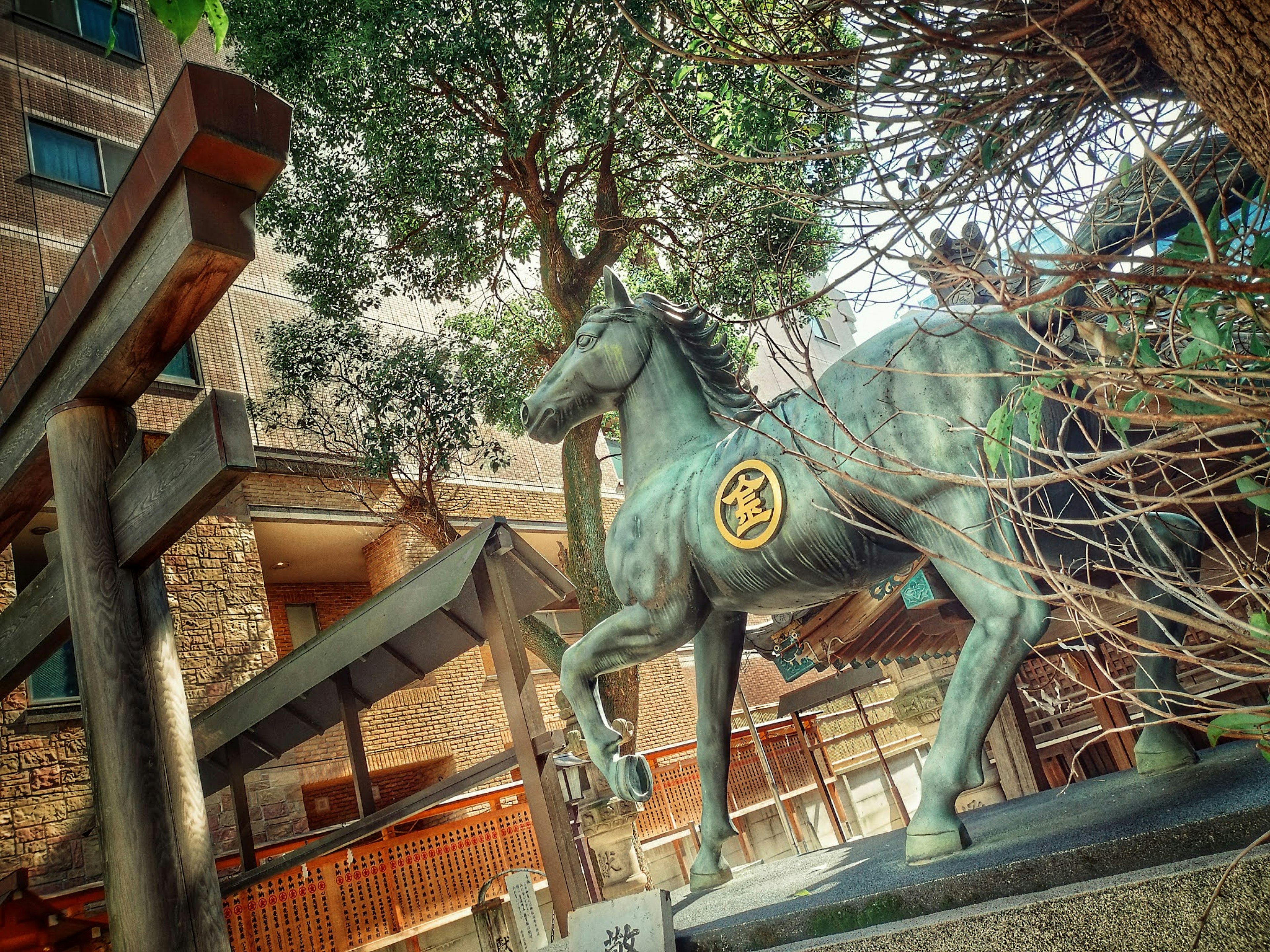 A statue of a horse at a shrine surrounded by green trees and foliage