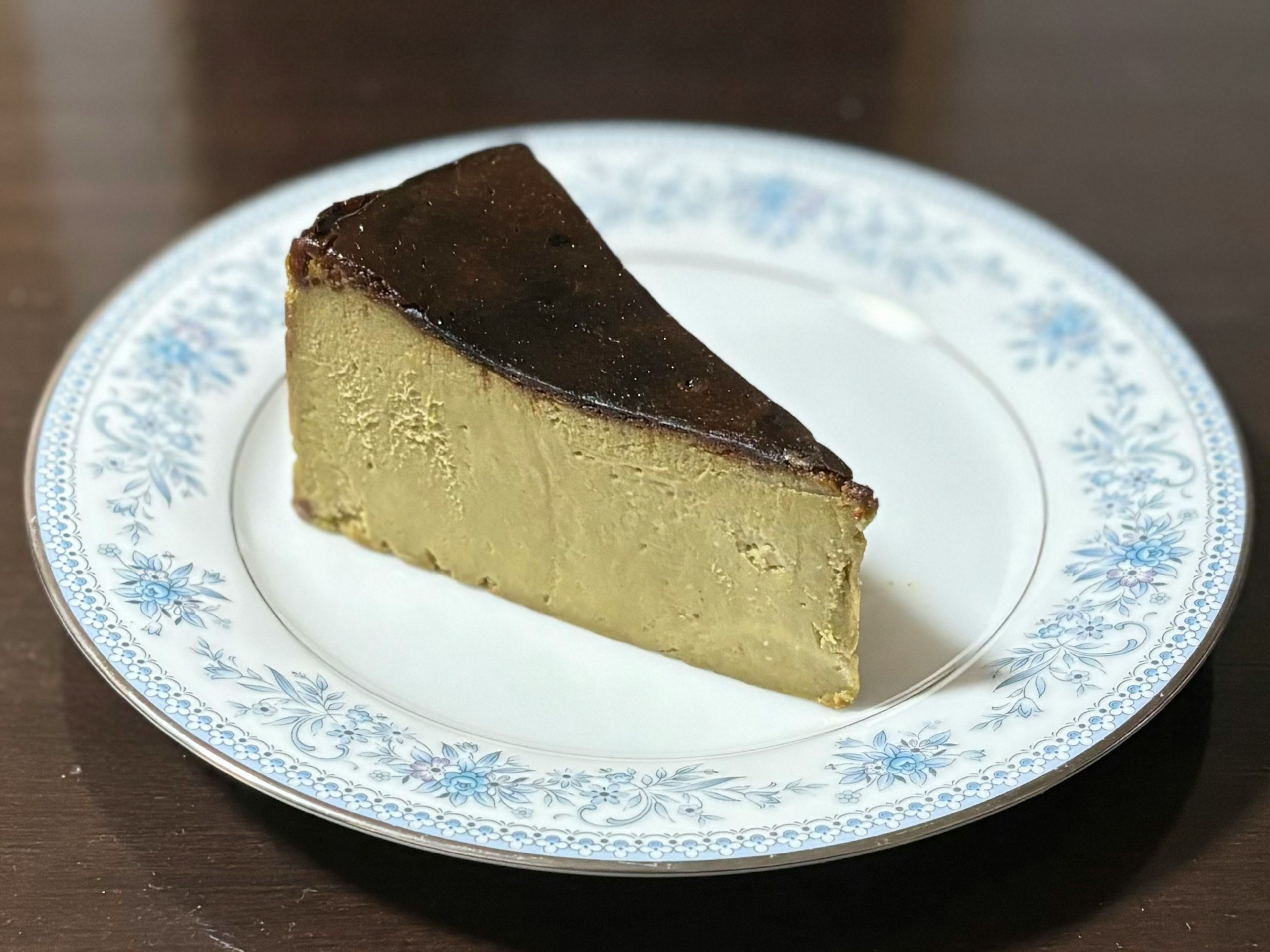 A slice of creamy cheesecake on a blue floral plate