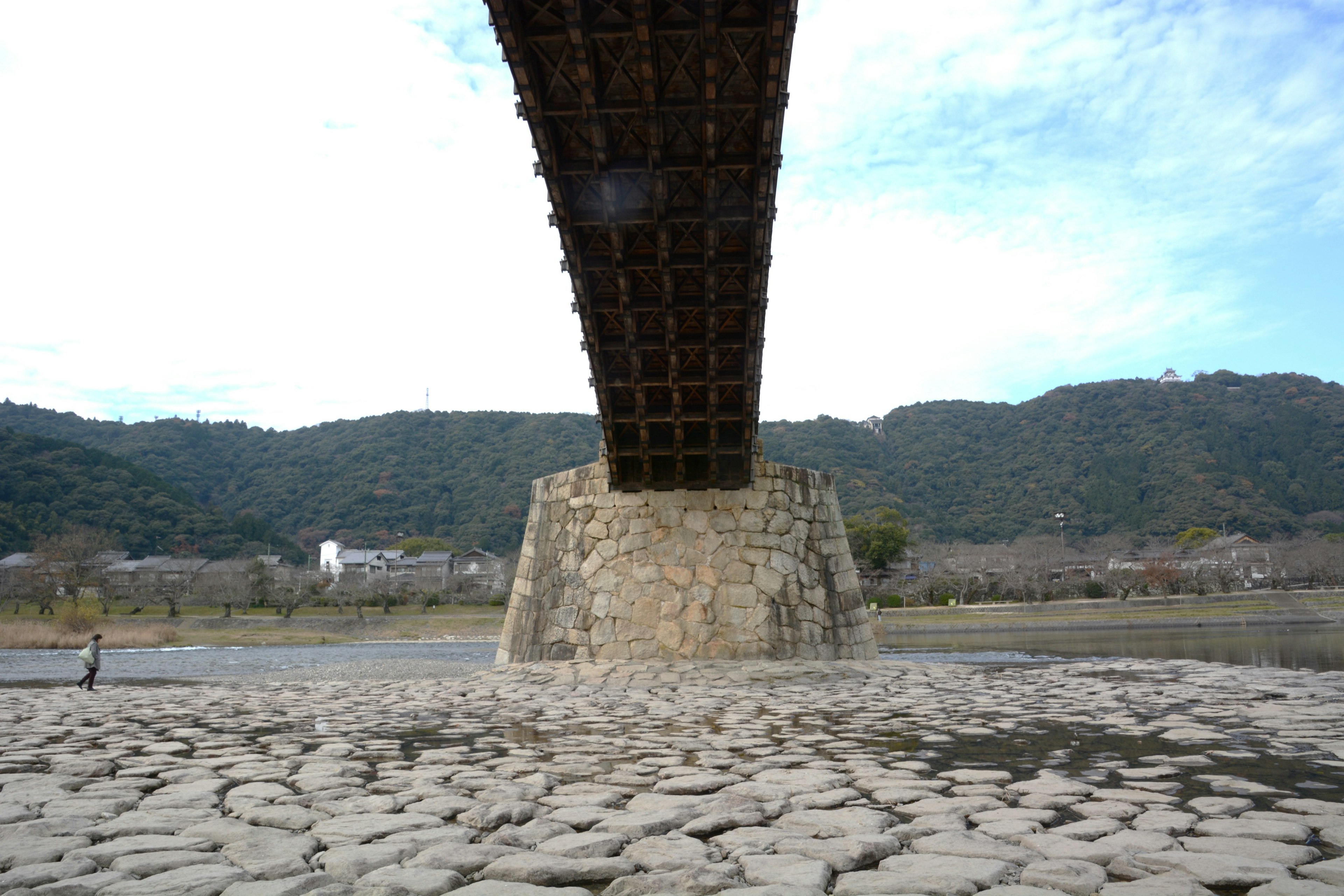 Wooden bridge supported by stone pillars over a dry riverbed