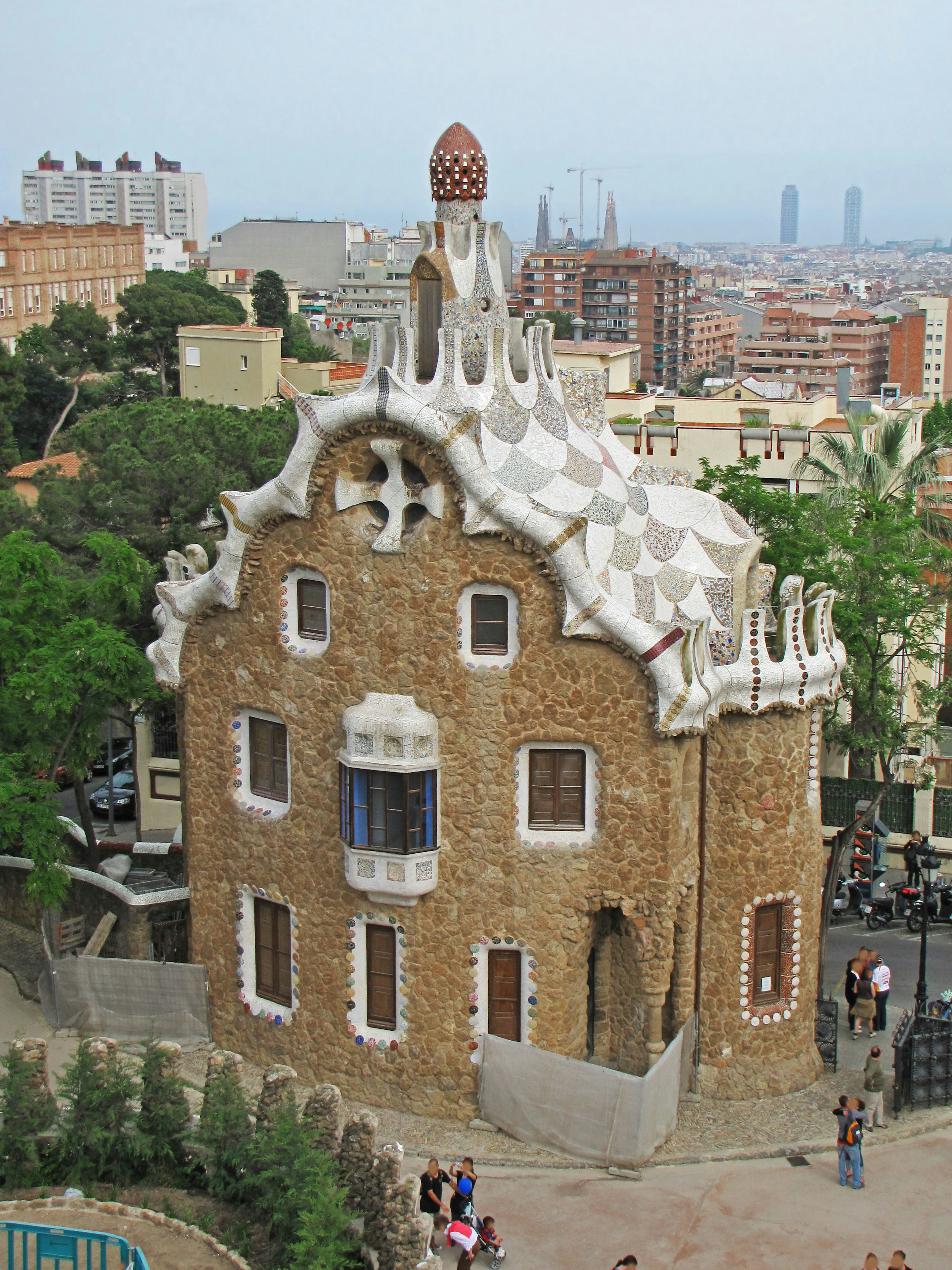 Unique building in Park Güell Barcelona featuring a wavy white roof and stone facade