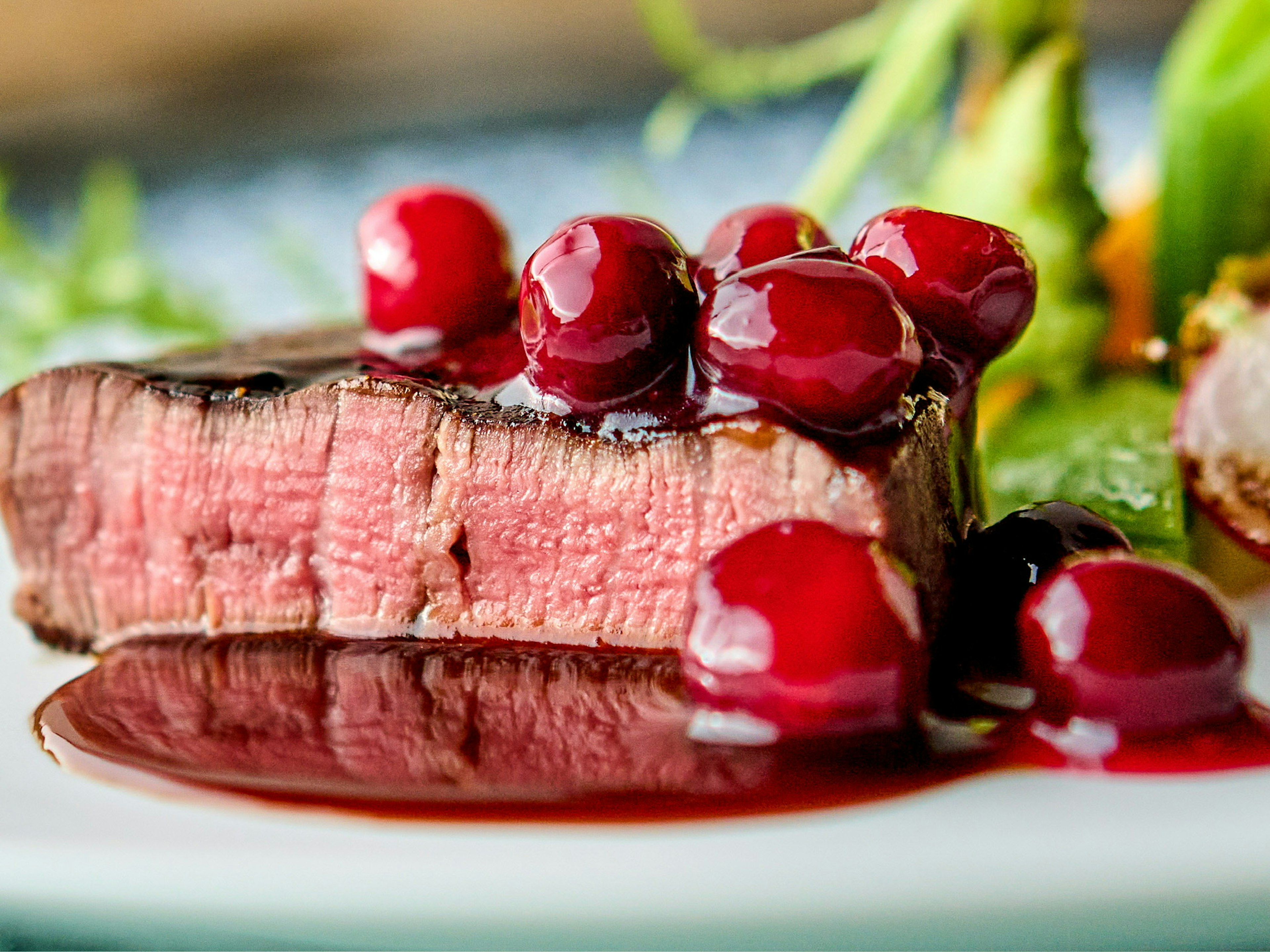 Close-up of a steak topped with cranberry sauce and garnished with berries