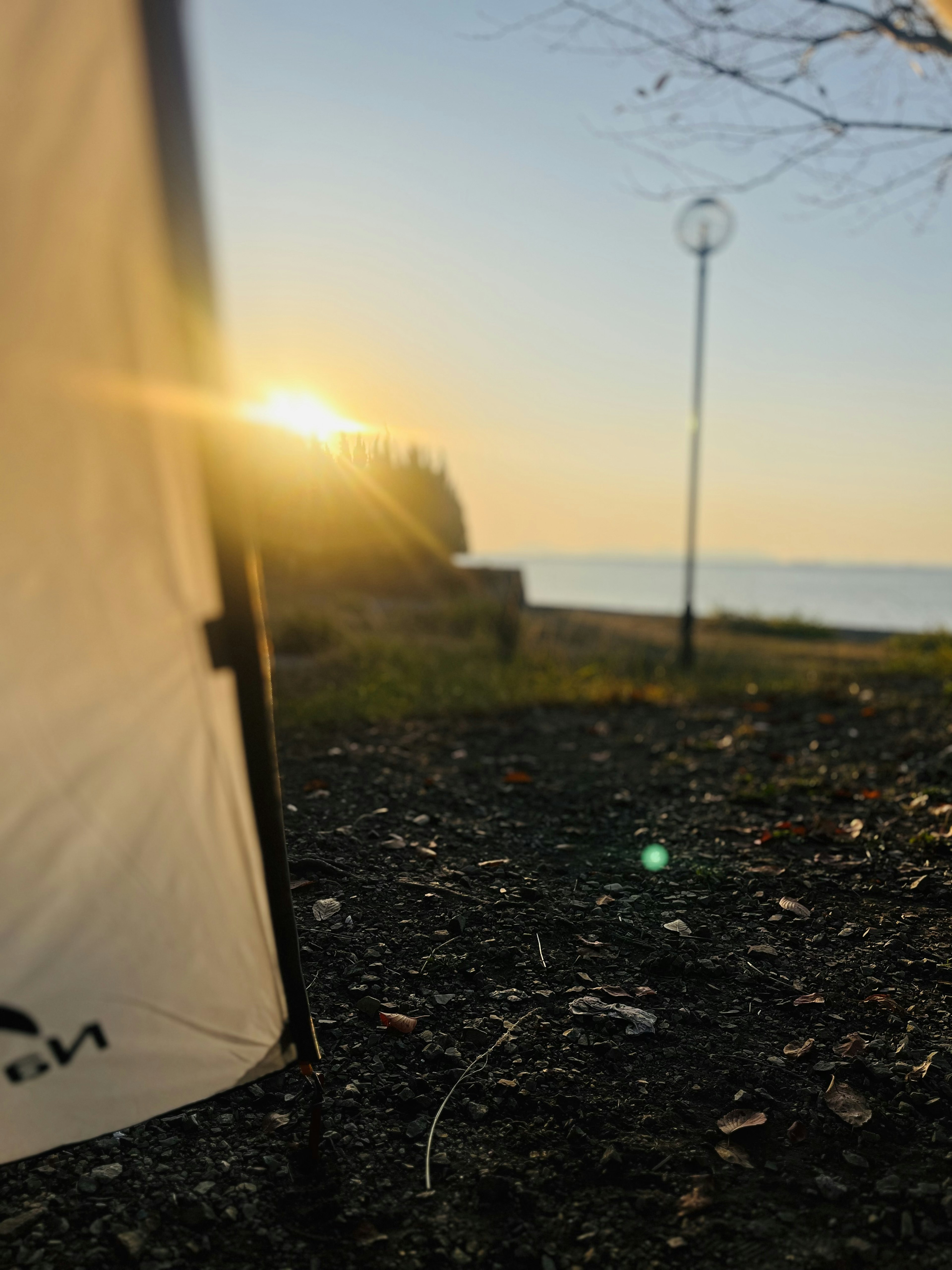 Vue latérale de la tente avec le coucher de soleil sur la mer et une zone herbeuse