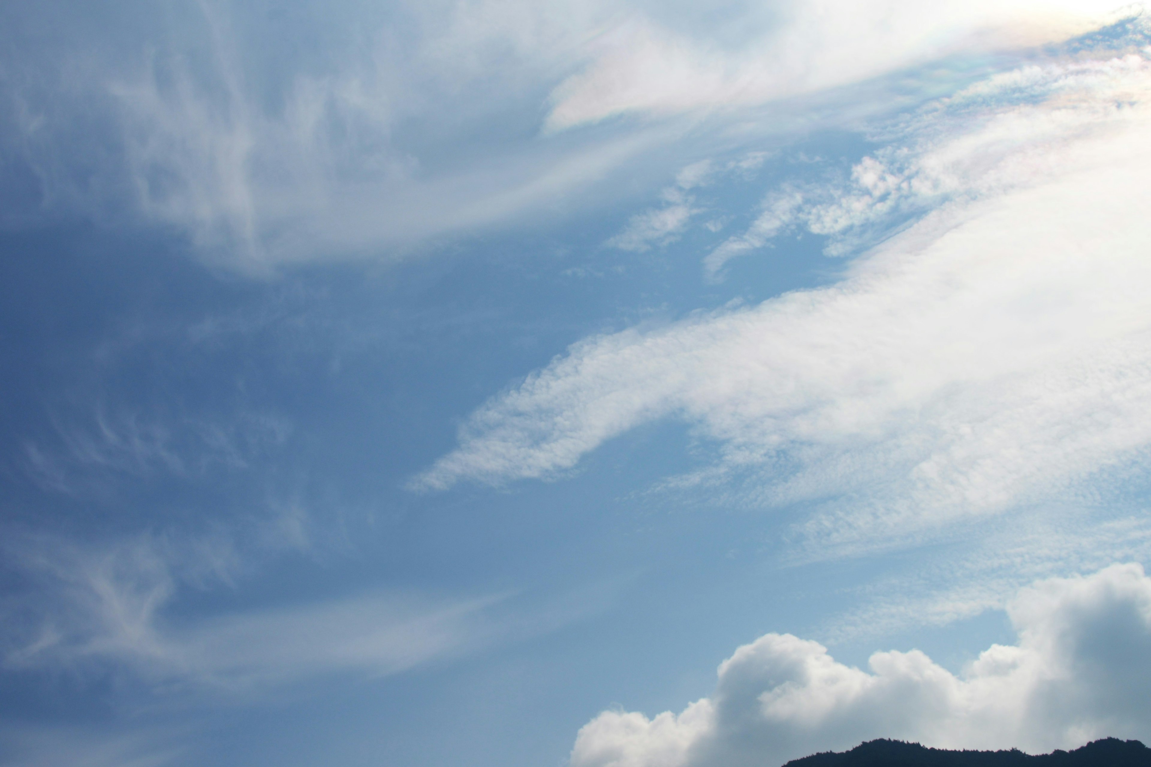 Cielo azul con nubes blancas y silueta de montaña