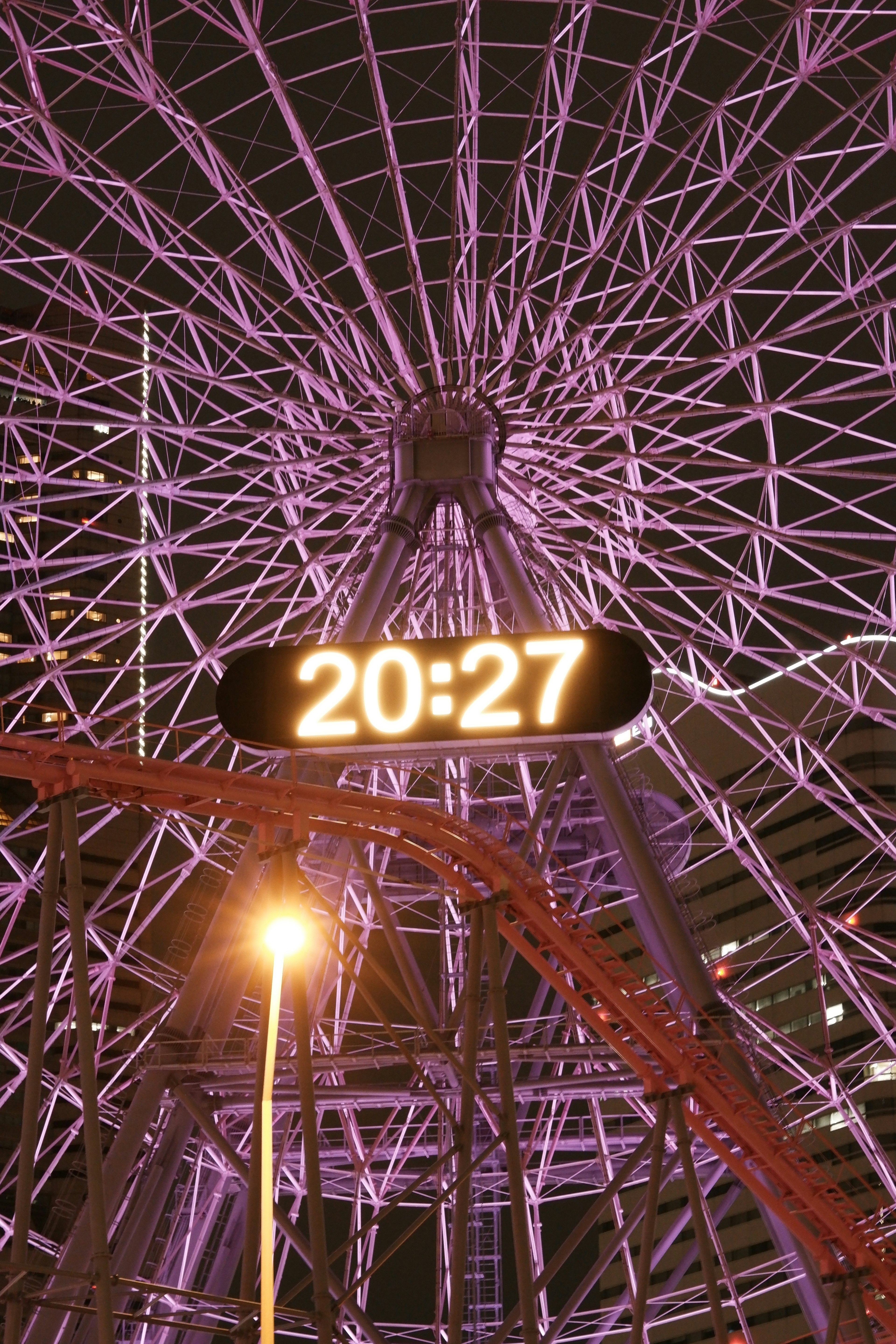 Night view featuring a purple Ferris wheel and a digital clock displaying 20:27