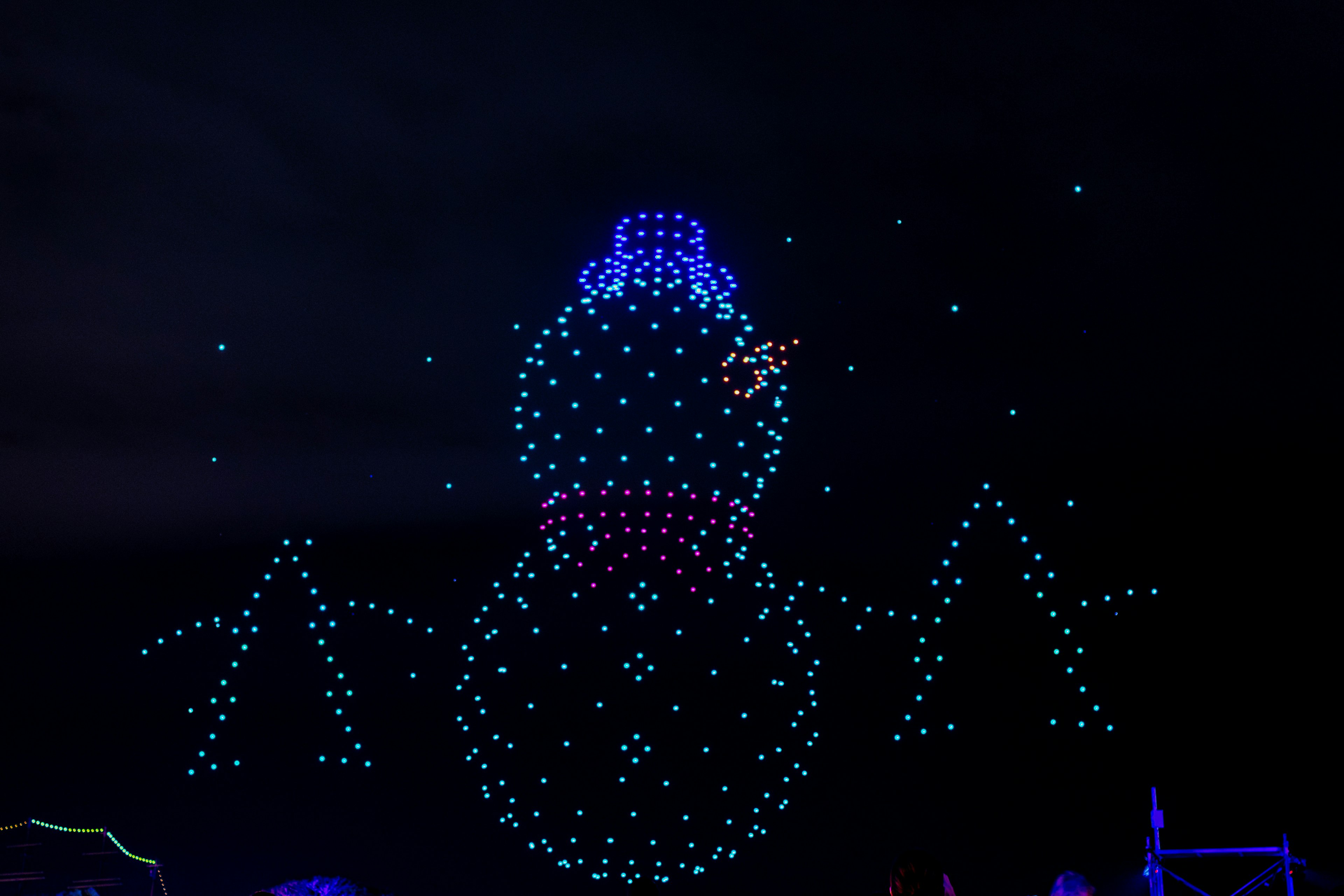 Illuminated snowman wearing a blue hat glowing against a dark background