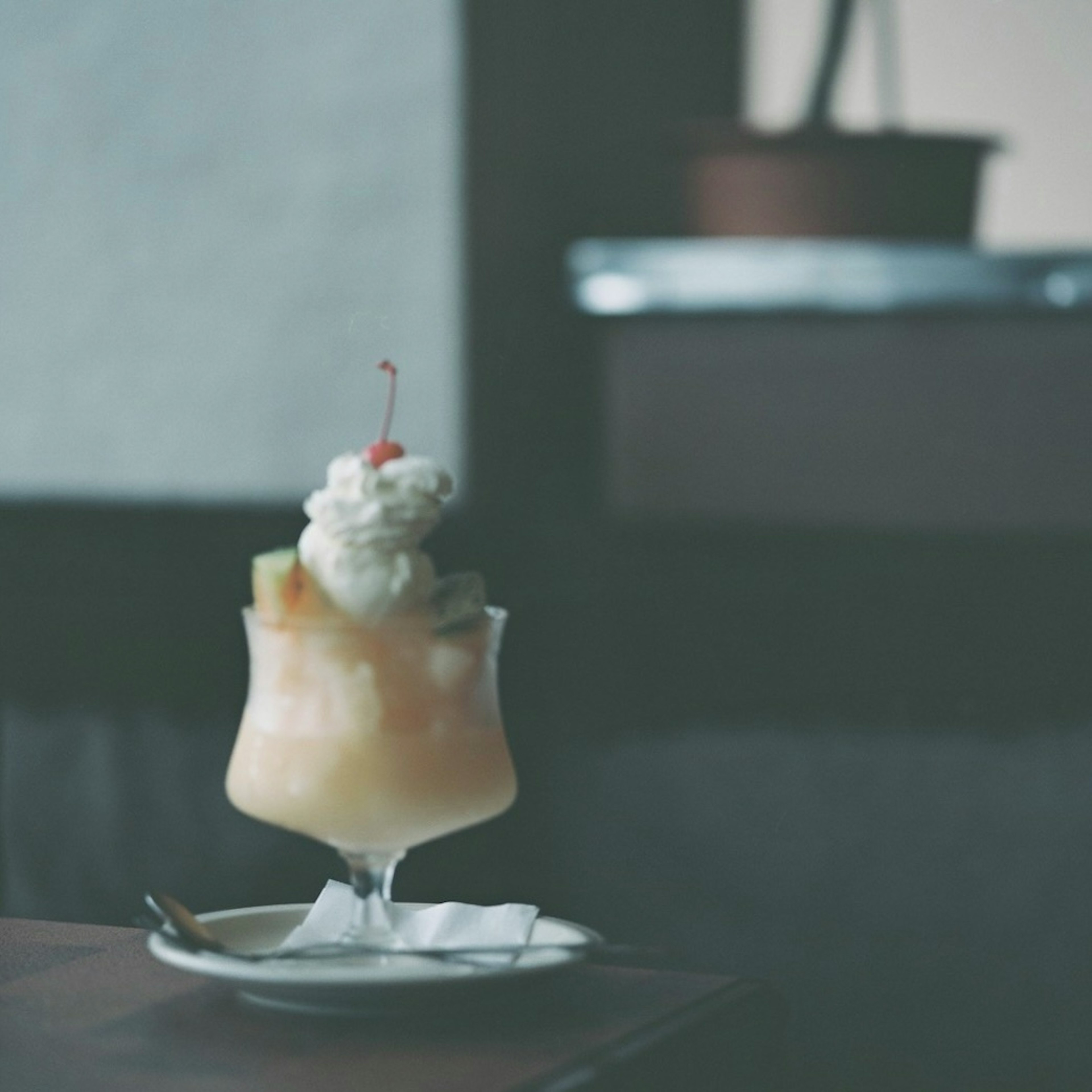 A fruit sundae topped with cream and a cherry sits on a table