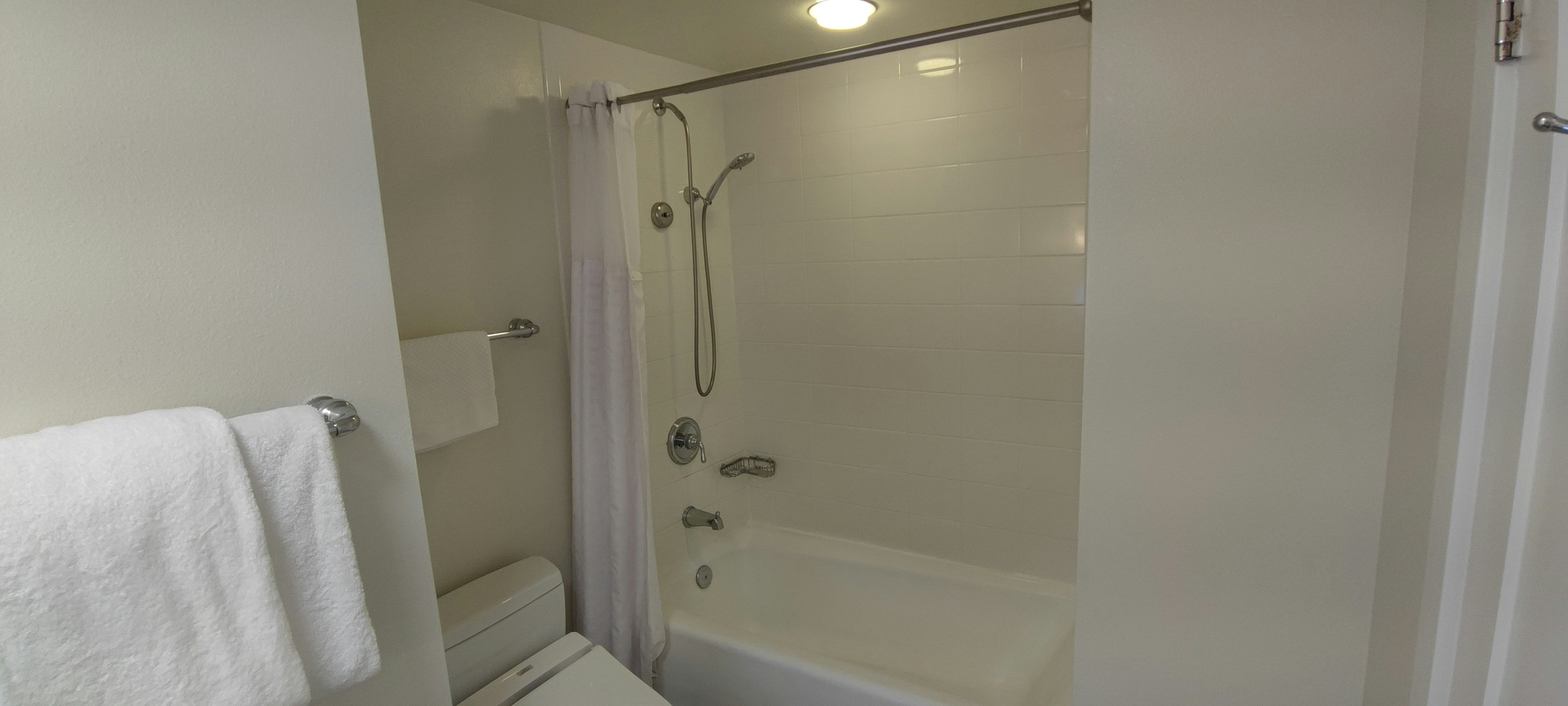 White bathroom featuring a bathtub and shower setup