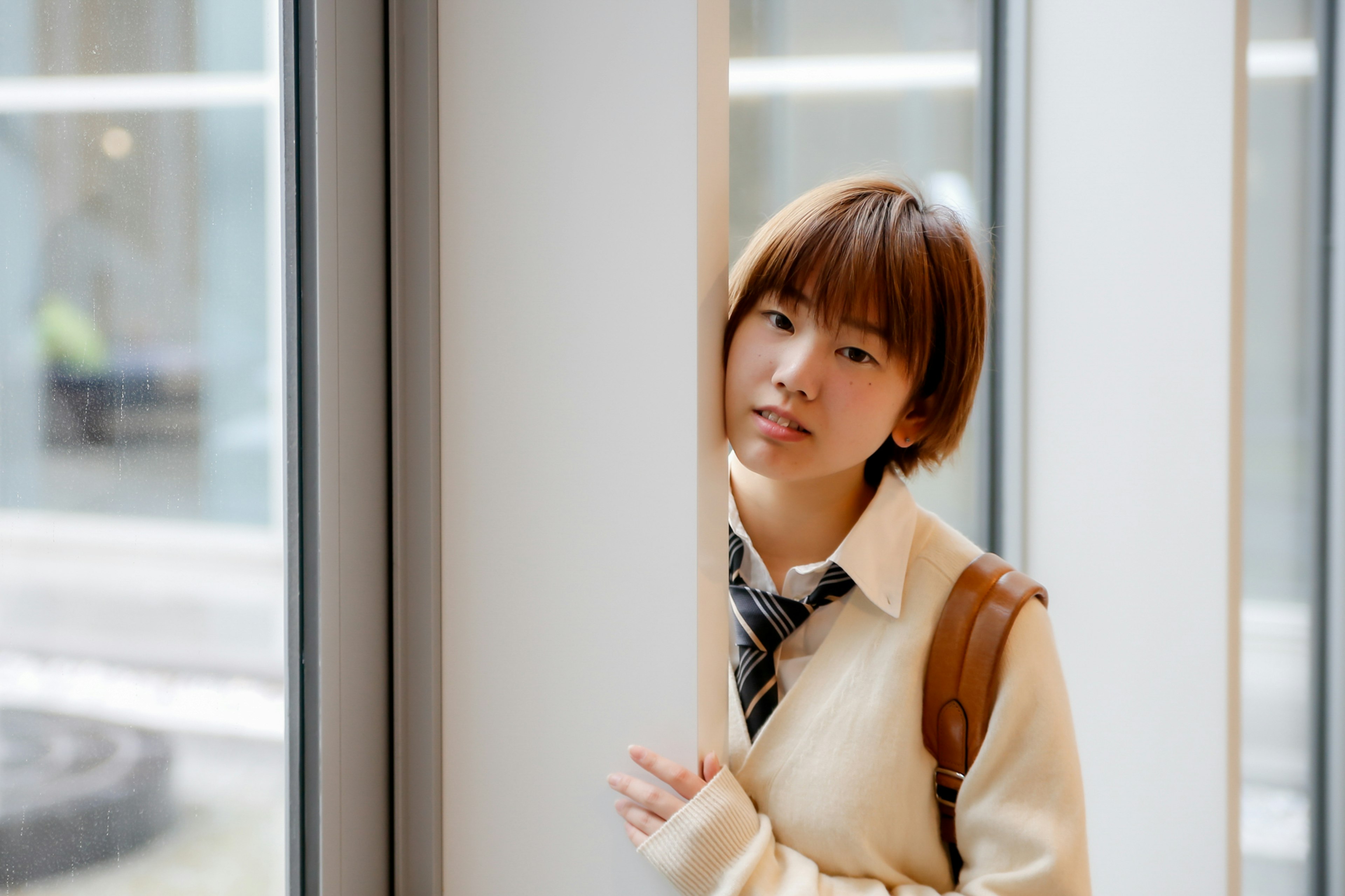 Young woman standing by a window leaning against a pillar