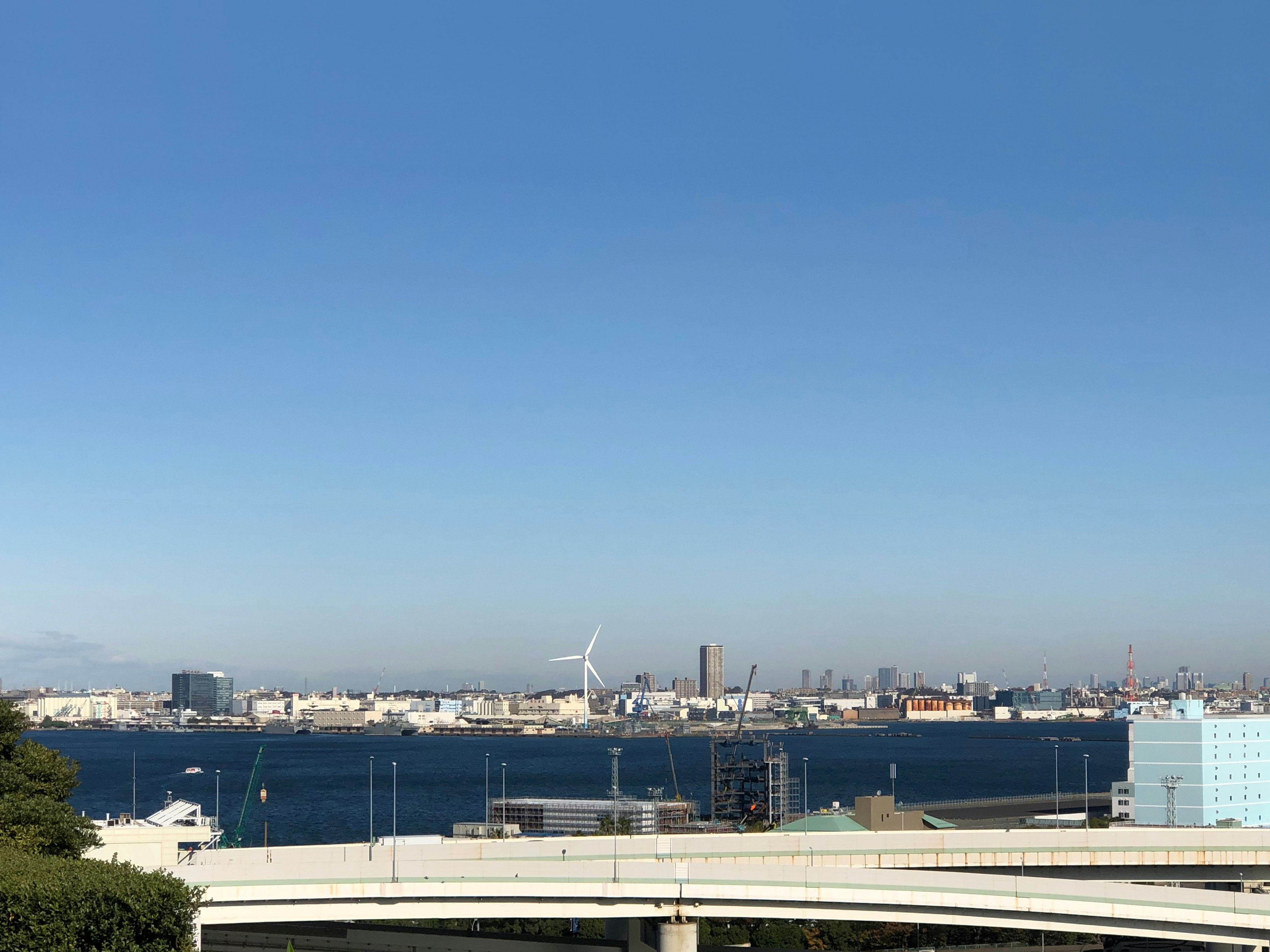 Skyline della città con vista sull'oceano sotto un cielo blu chiaro con turbine eoliche e grattacieli