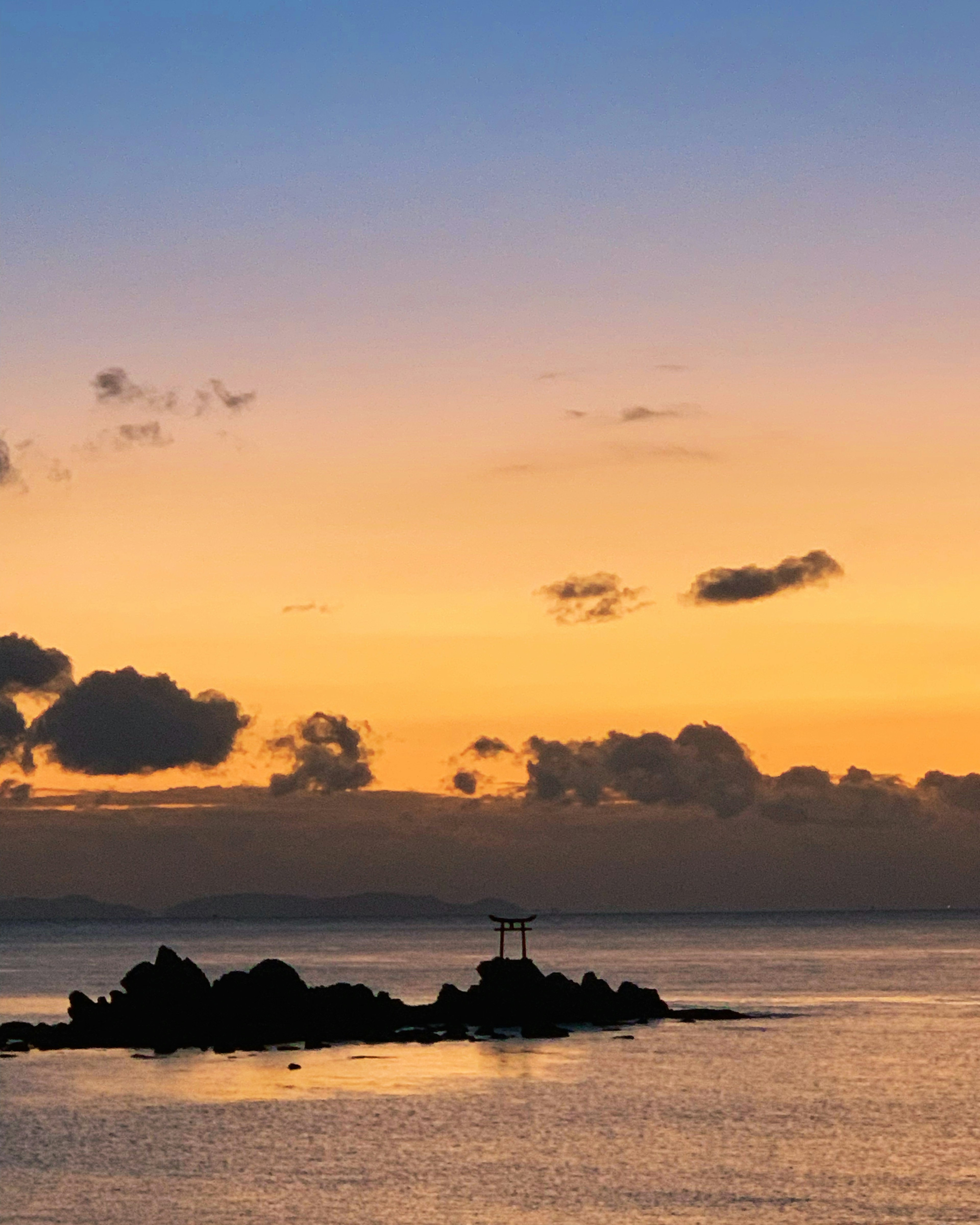 Magnifique coucher de soleil sur l'océan avec une croix sur les rochers et un ciel orange