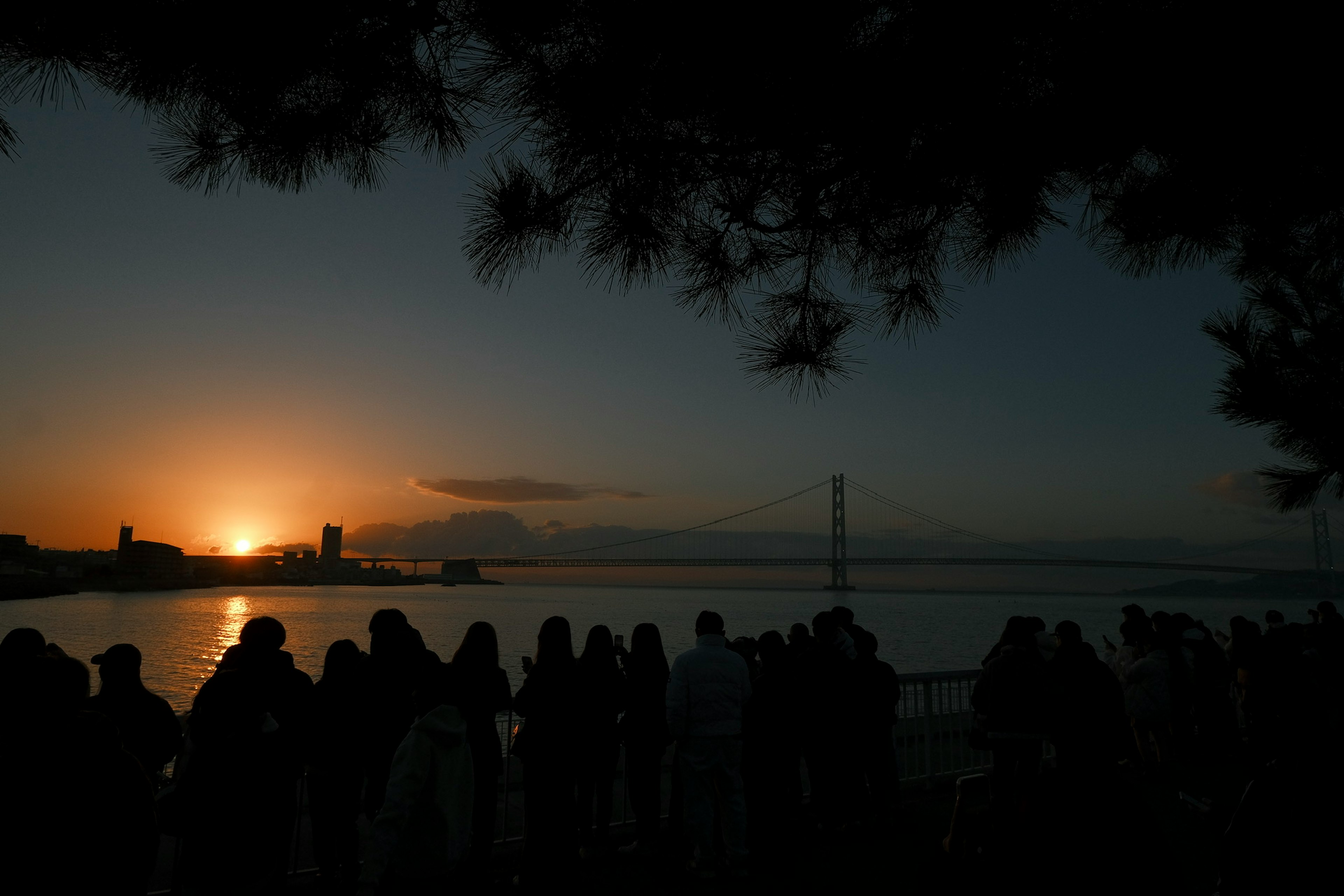 Silhouetten von Menschen, die den Sonnenuntergang am Meer beobachten