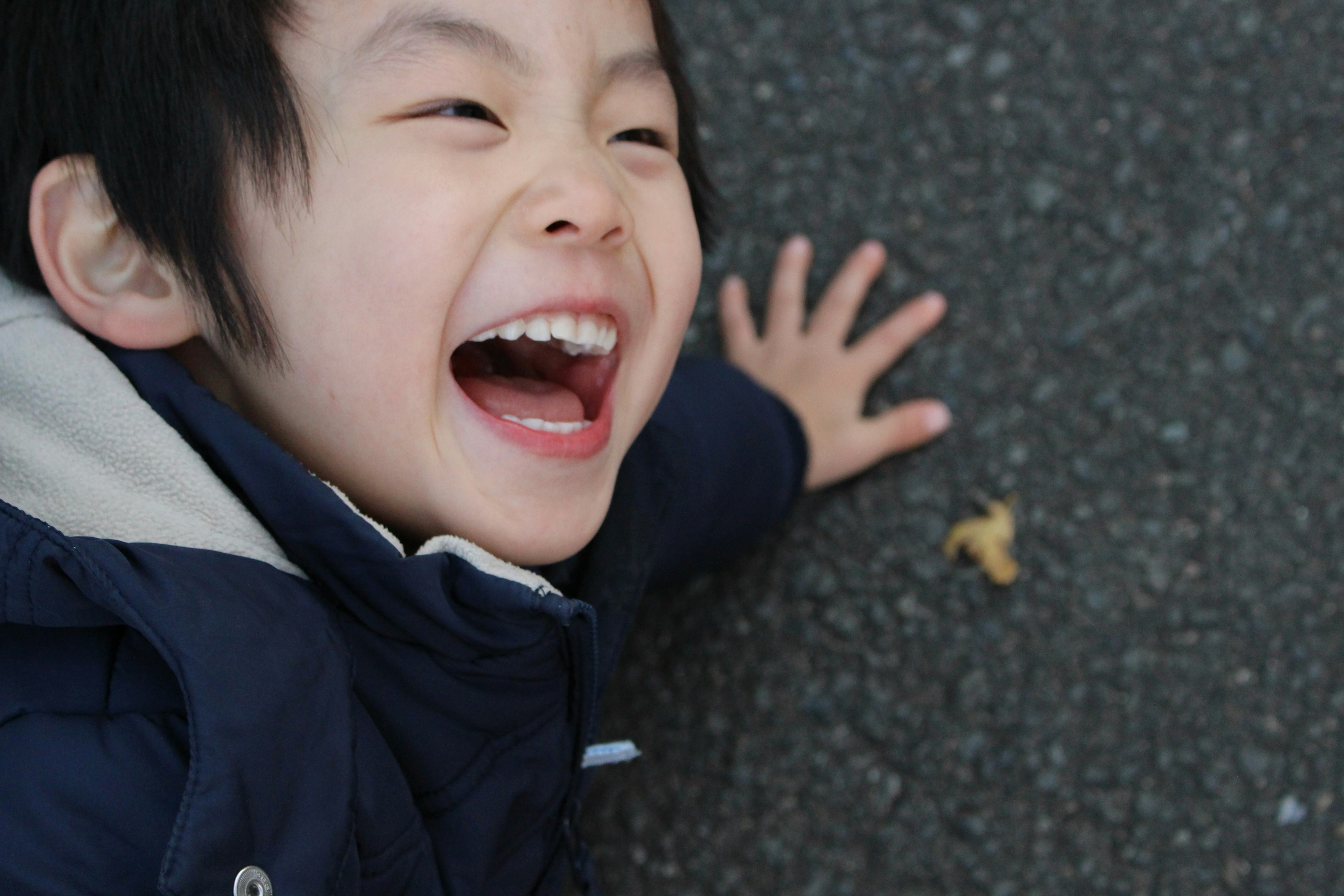 笑顔で地面に横たわる子供の写真