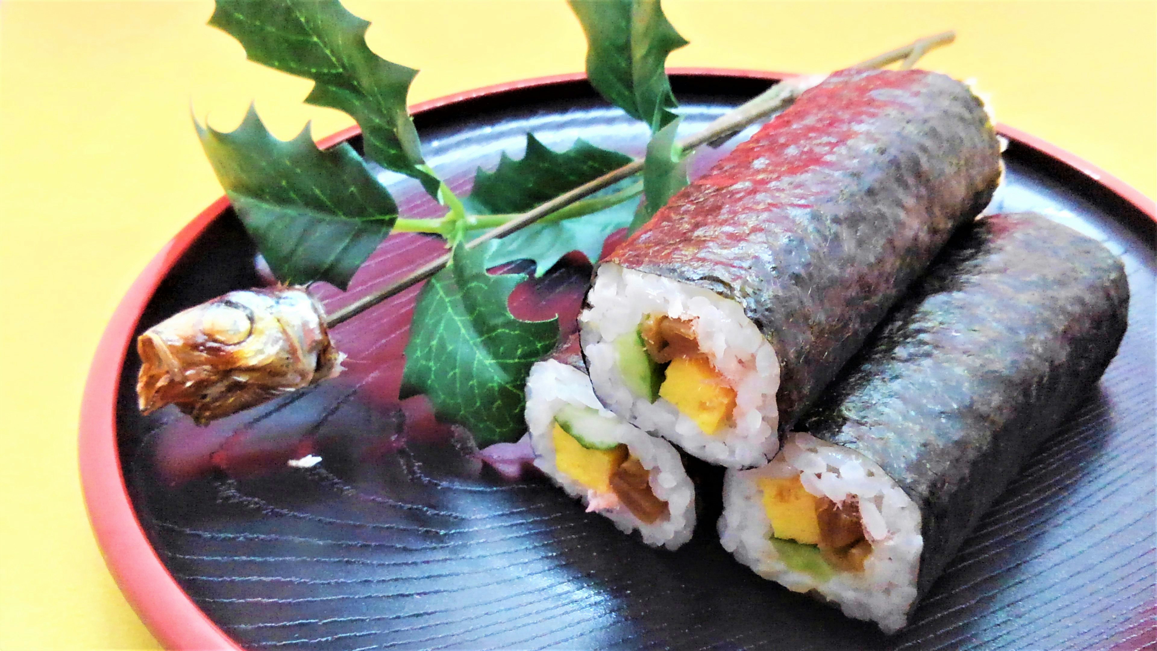 Gulung sushi di atas piring dengan daun dekoratif