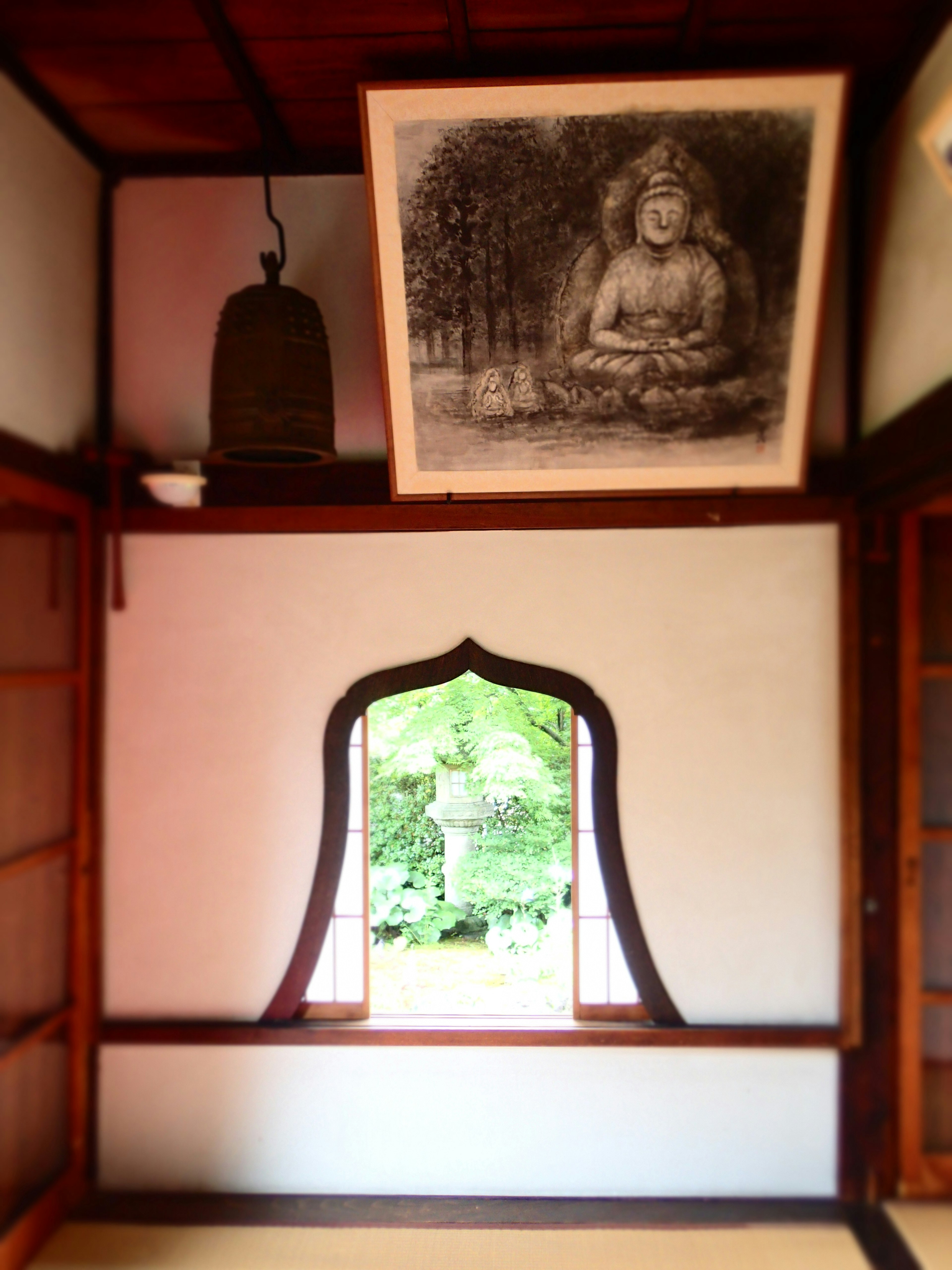 Serene room featuring a large Buddha painting and greenery visible through the window