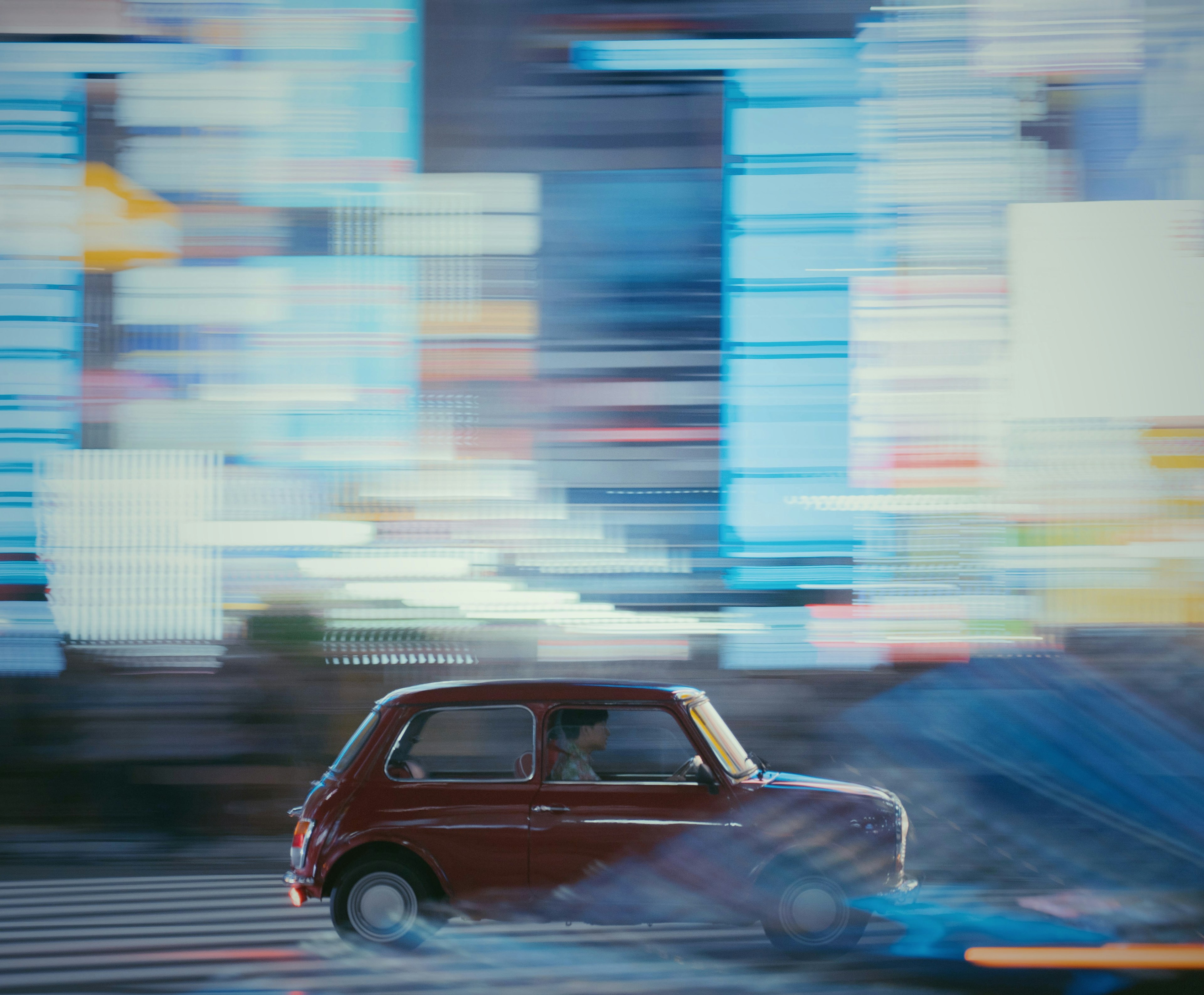 A red car speeding through a vibrant city background