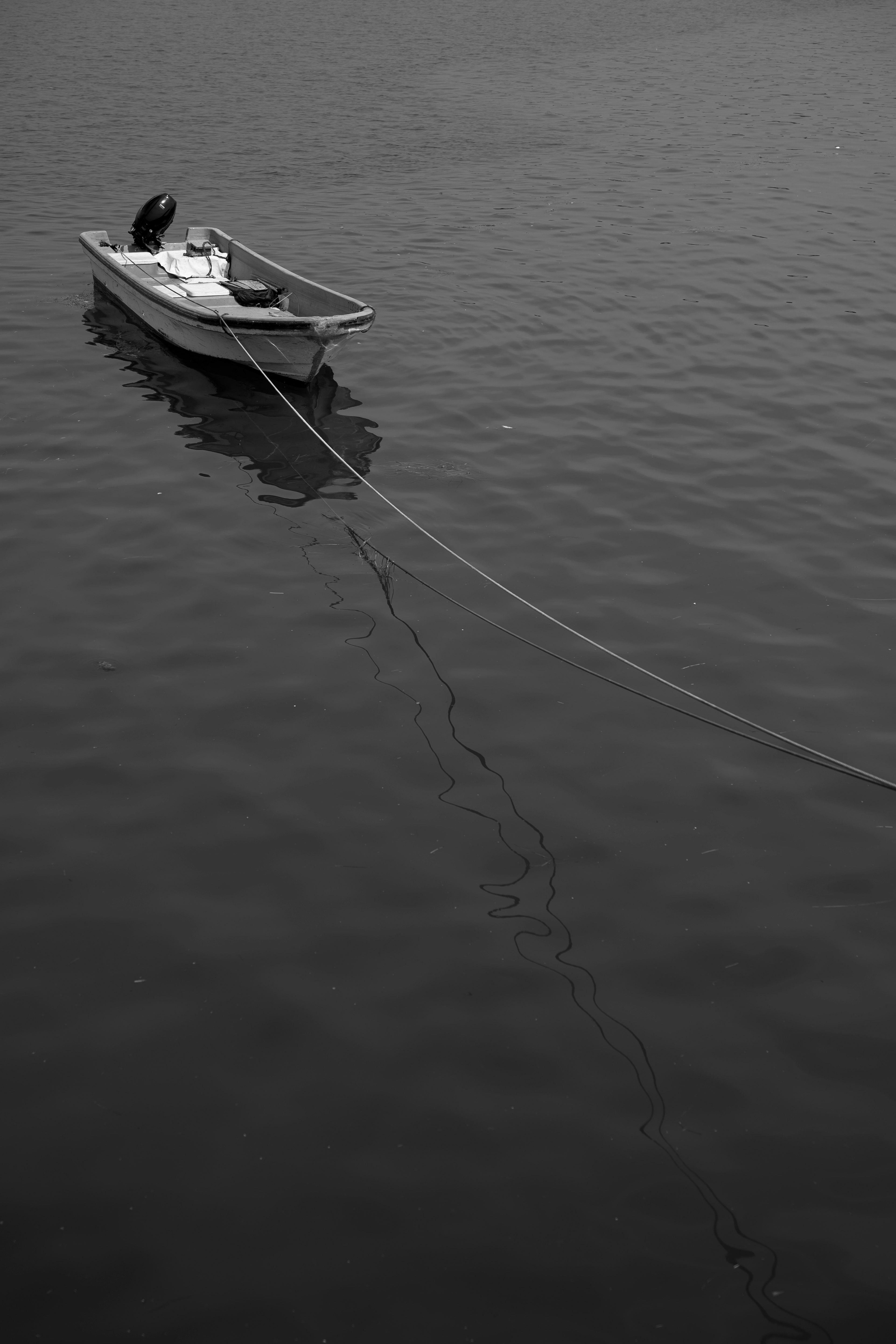 Un pequeño bote flotando en agua tranquila con una cuerda larga