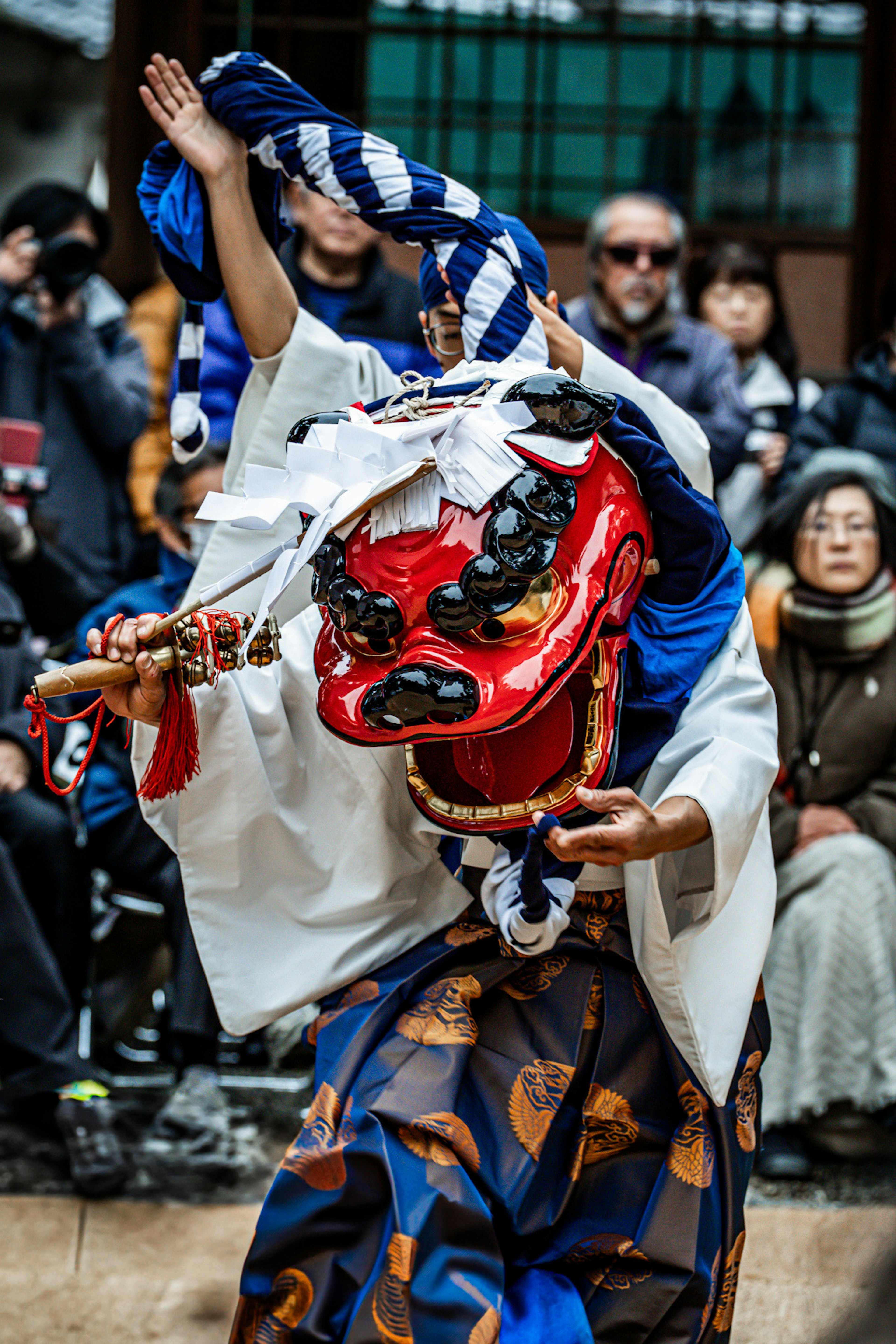 Traditional dancer wearing a red lion mask performing a dance