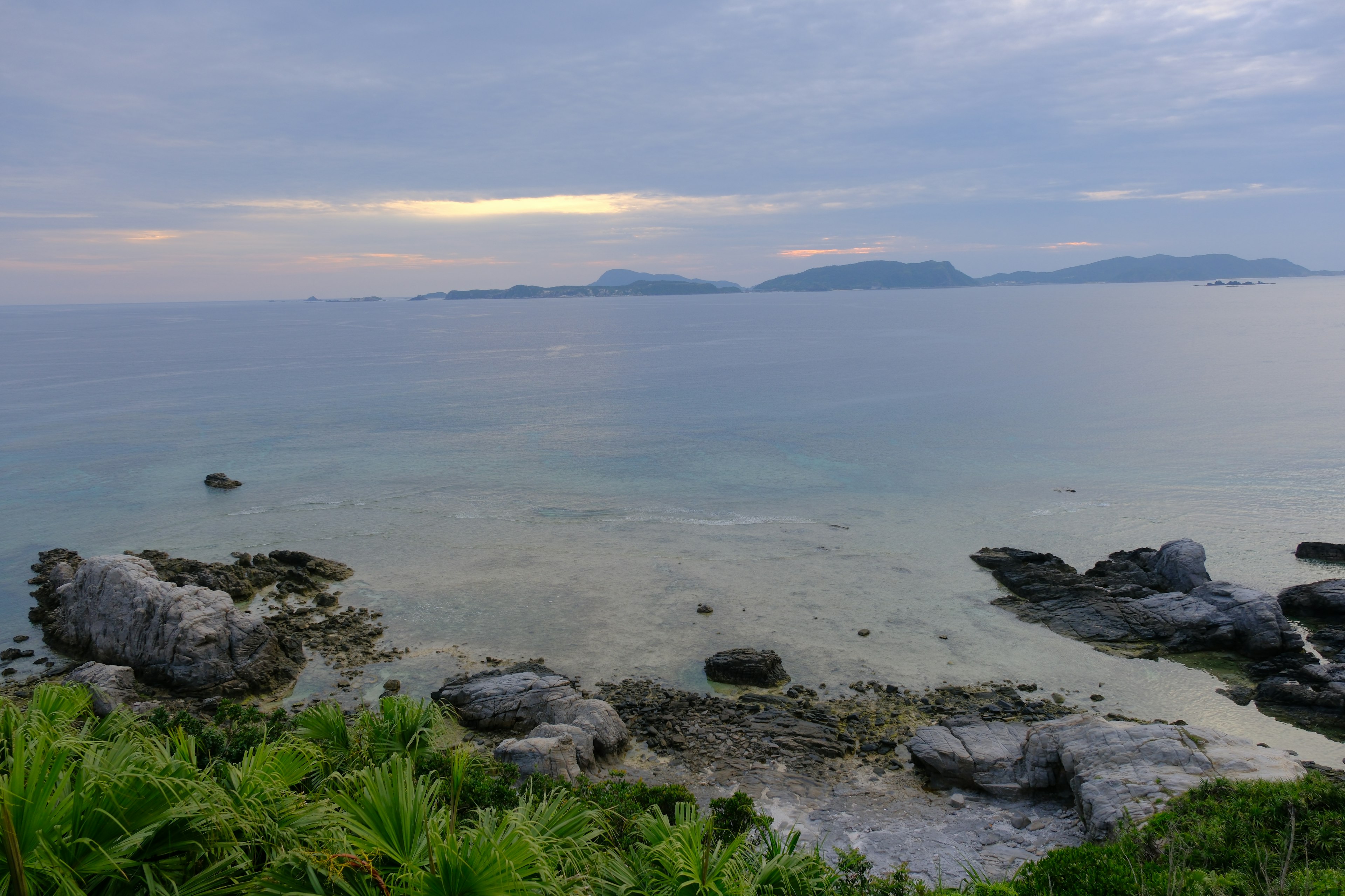 Calm seascape featuring distant islands and rocky shoreline