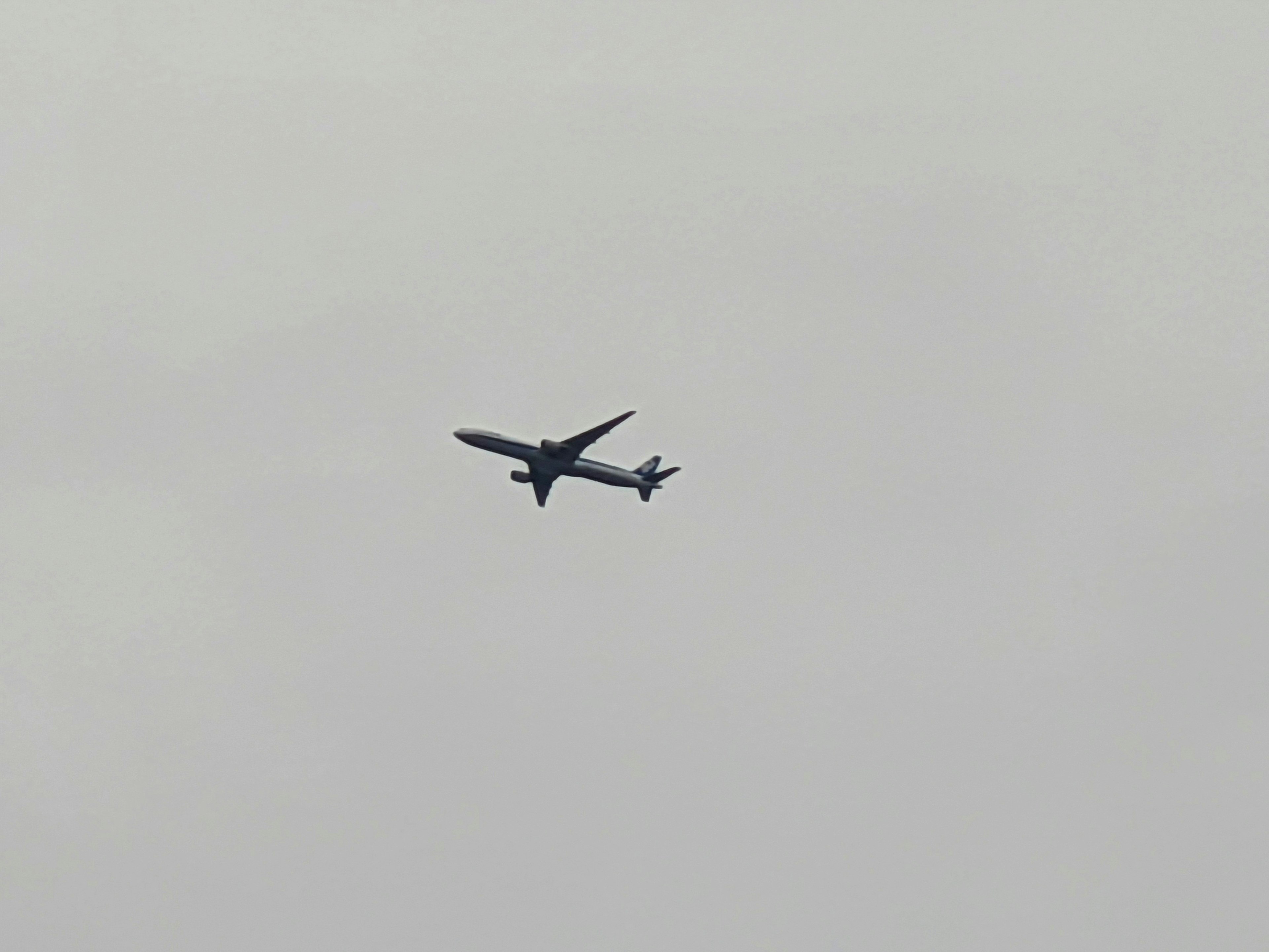 An airplane flying in a gray sky