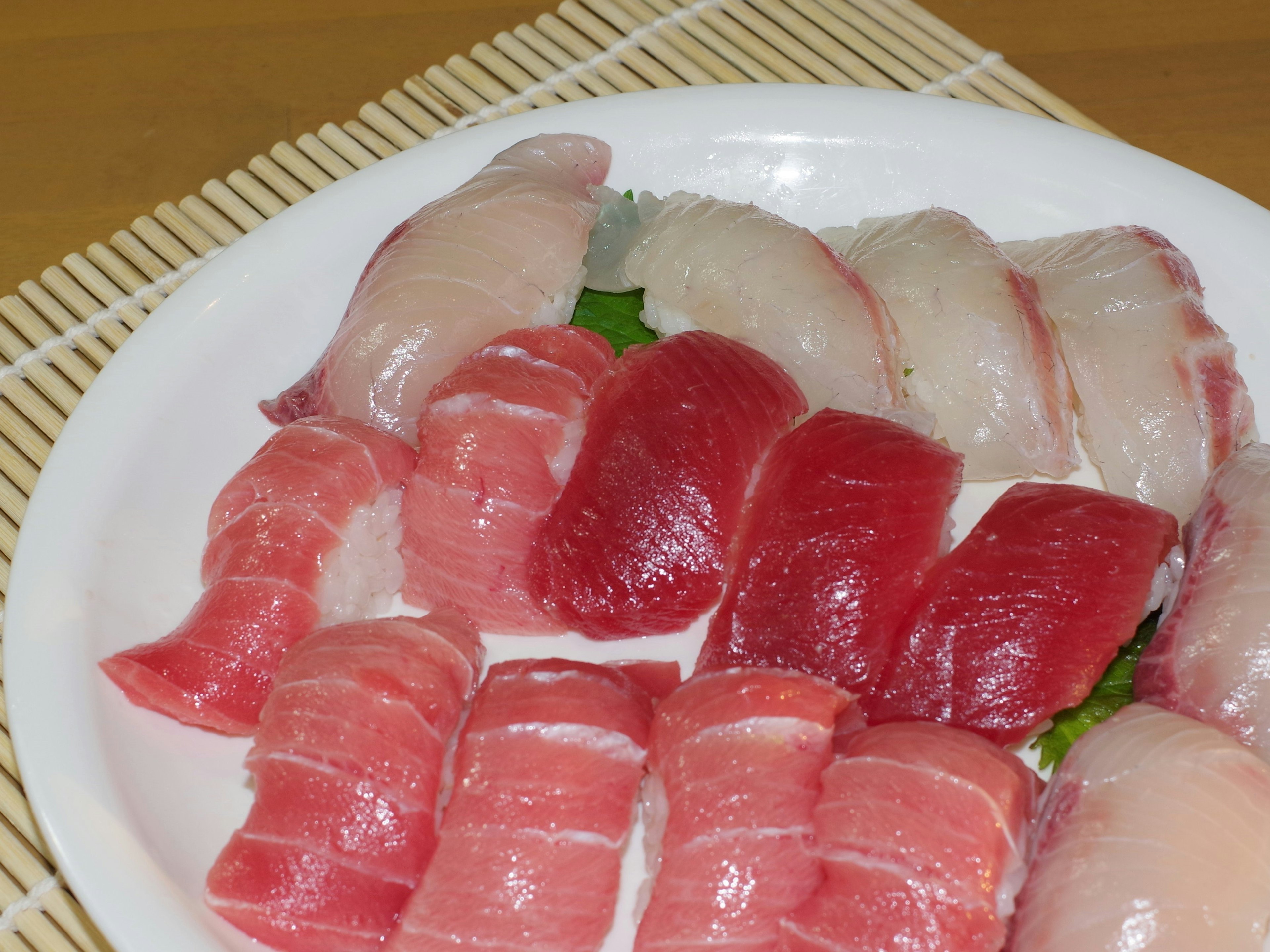 Un piatto di sushi fresco con fette di tonno e pesce bianco colorato