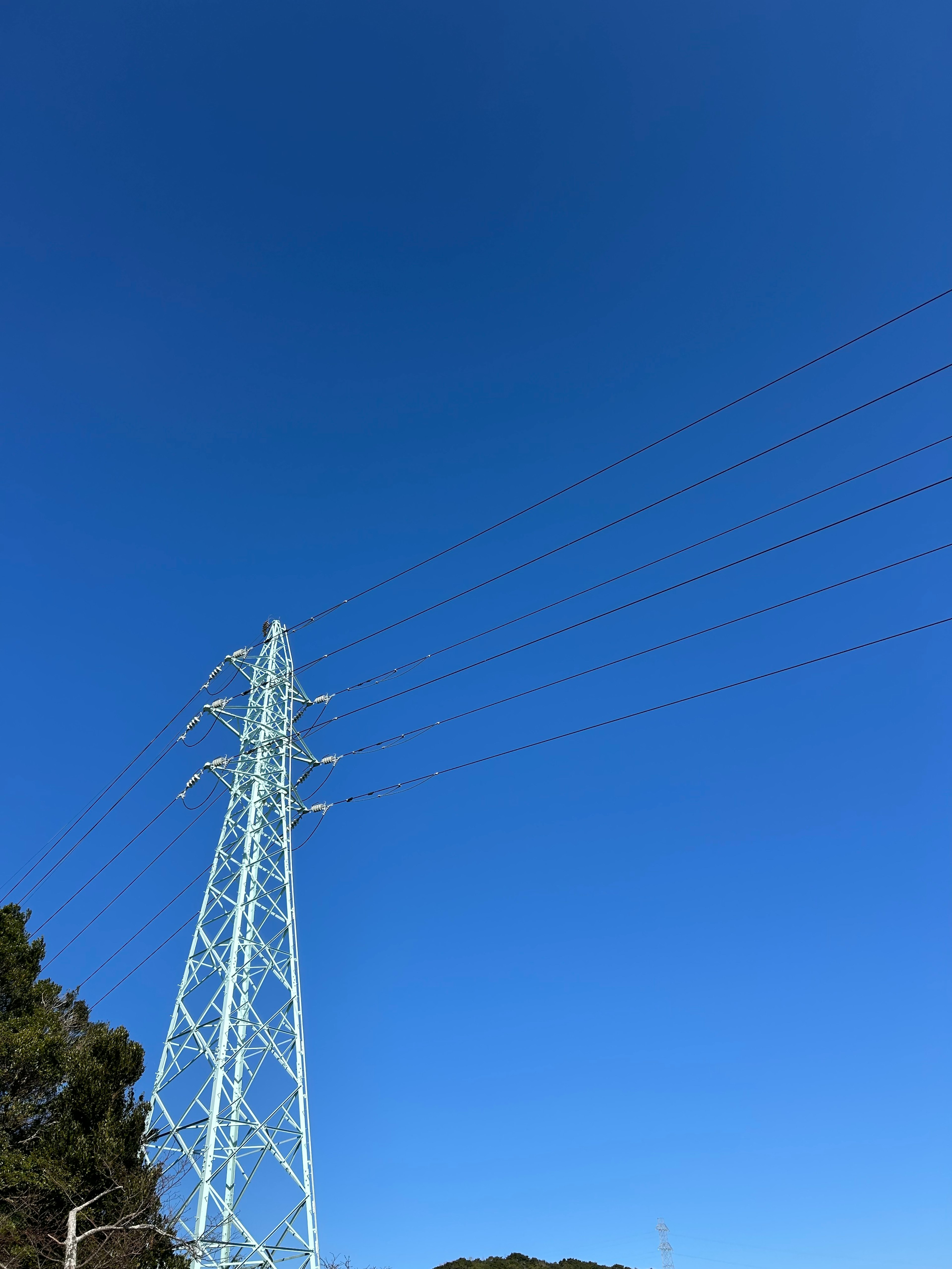 Torre de alta tensión bajo un cielo azul claro