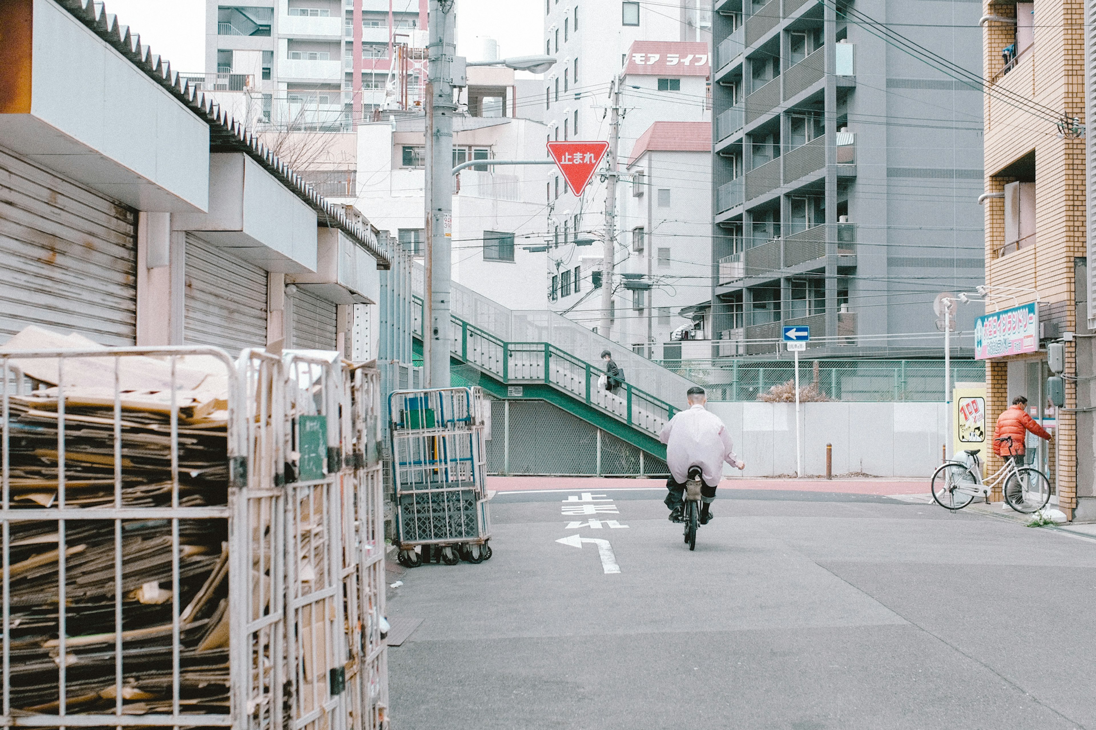 自転車に乗る男性が都市の通りを進む様子 繁華街の建物と交通標識が見える