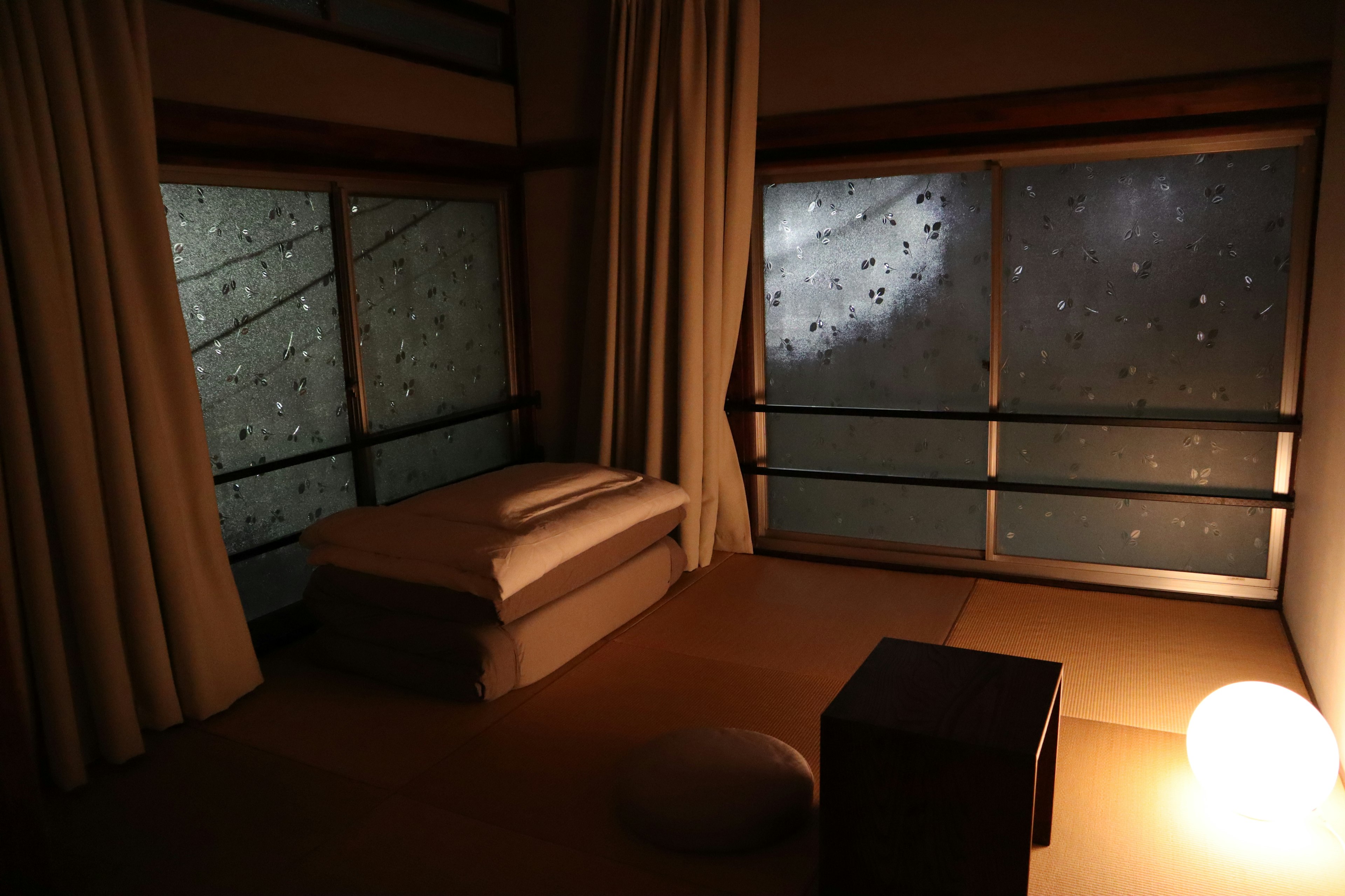 Japanese room on a rainy night, water droplets on windows, soft lighting, minimalist decor