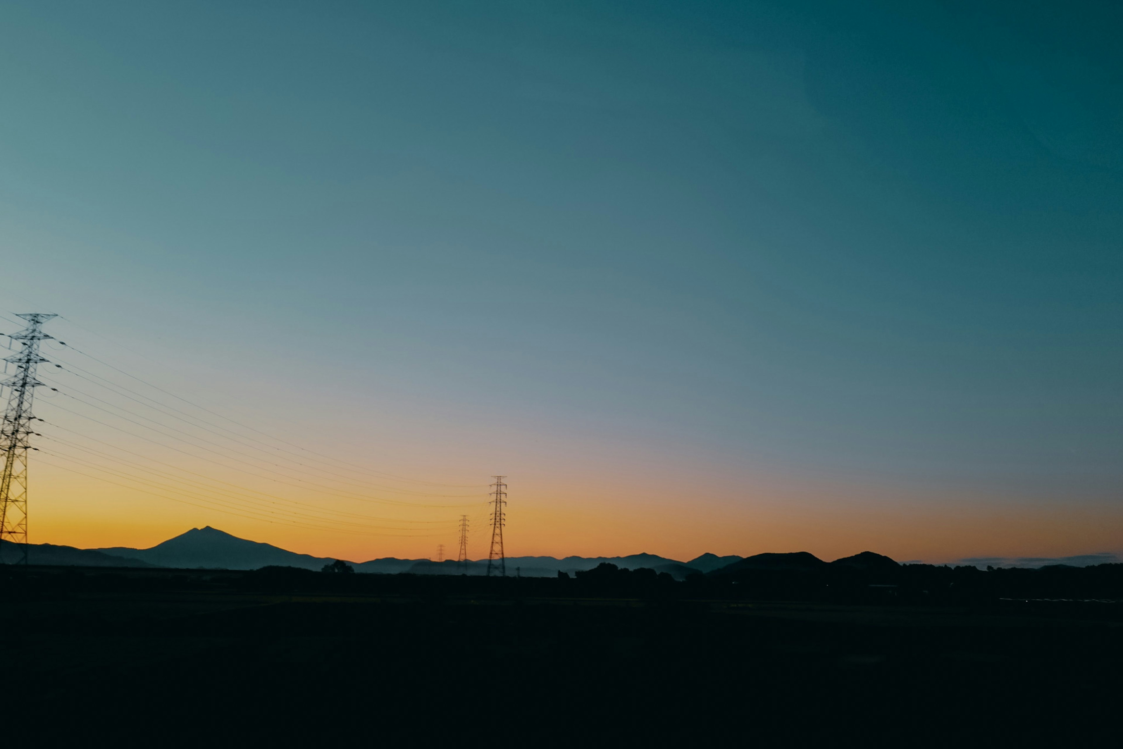 電線塔と山々が見える静かな夕暮れの風景