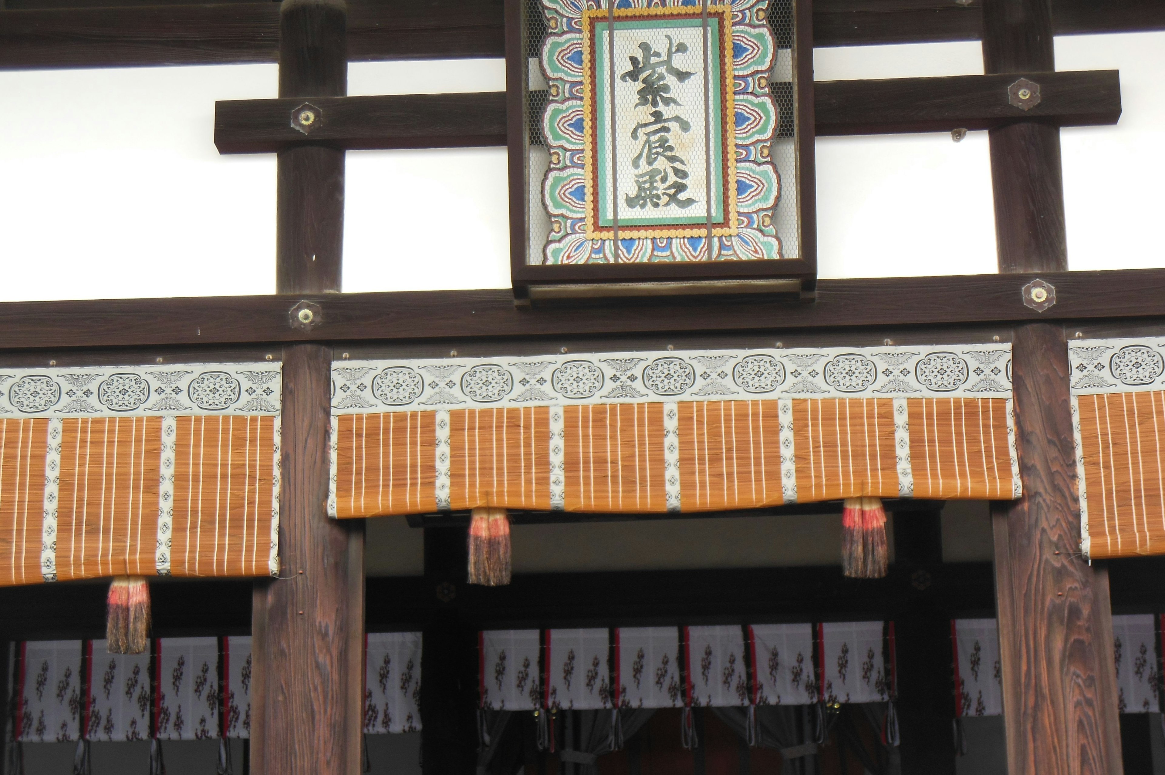 Entrance of a traditional Japanese building featuring a decorative sign and bamboo curtain