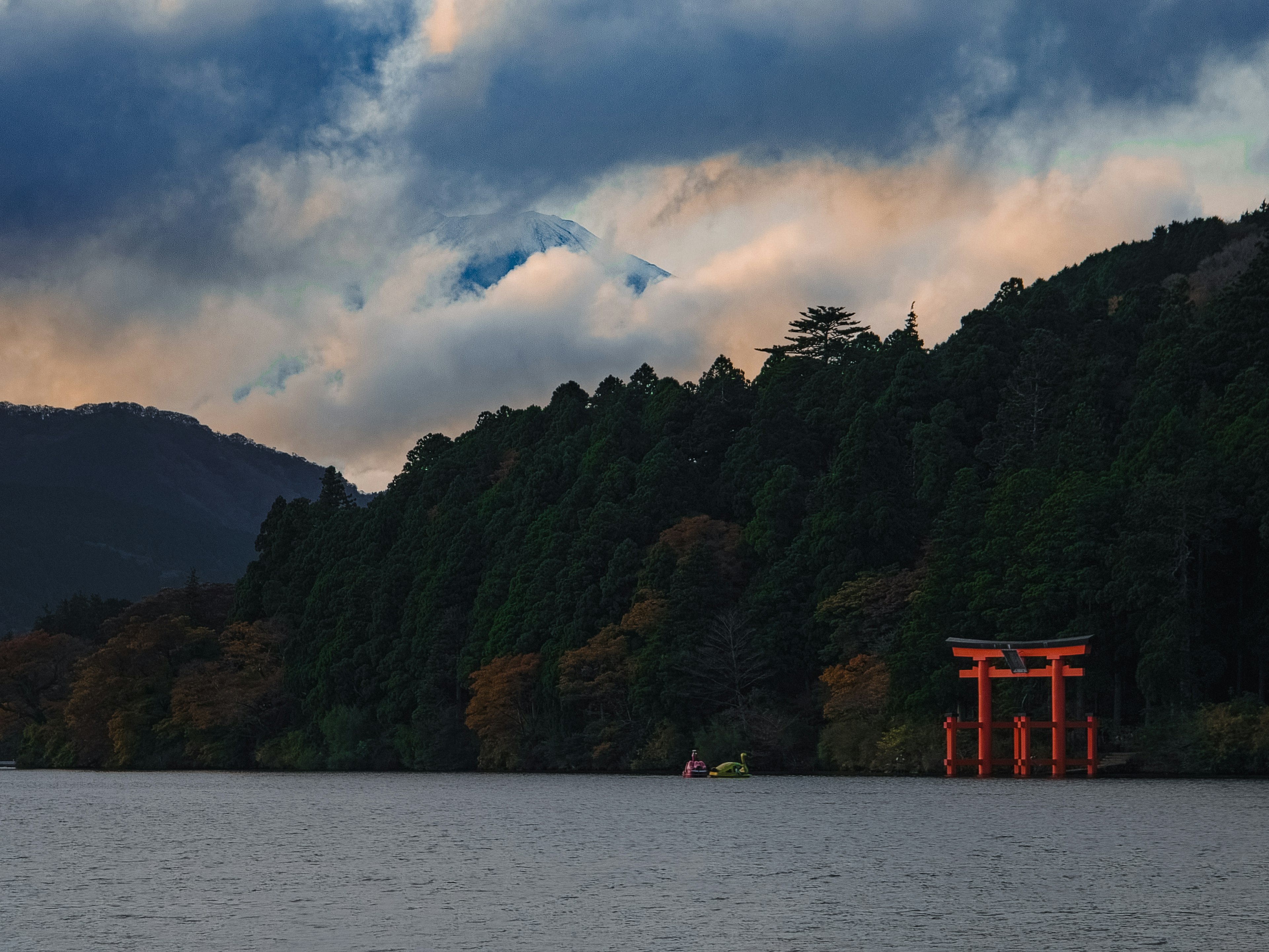 Khung cảnh của cổng torii đỏ gần hồ được bao quanh bởi núi